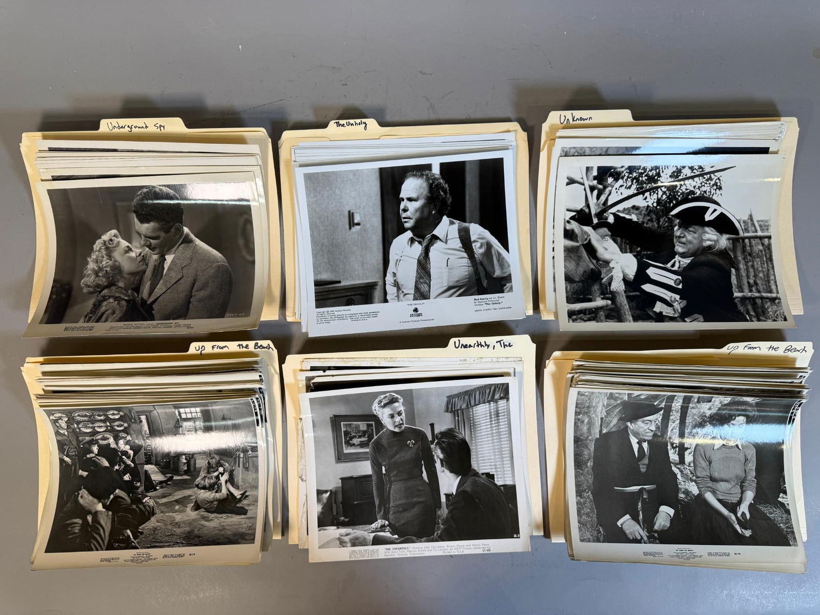 A Group of Vintage Film and Television Publicity Photographs: A group of manila file folders containing multiple black and white publicity photographs, primarily 8x10 inches in size. The folders are identified with content such as "Underground Spy," "The Unholy,