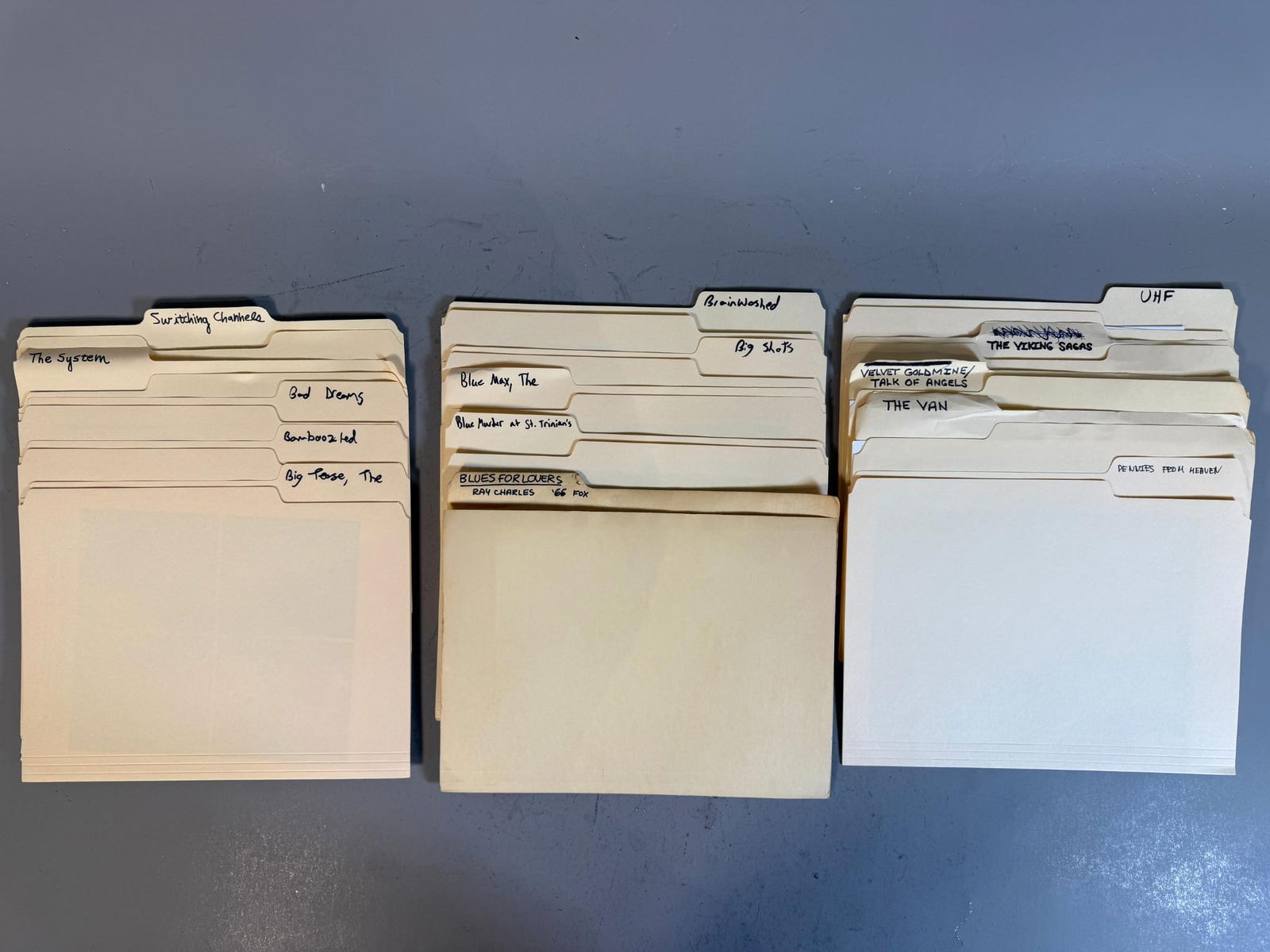 A Collection of Late 20th Century Film and Television Production Stills and Promotional Photographs: A group of light yellow manila file folders, organized into group of stacks, each containing numerous photographic prints. The contents are primarily black and white glossy film stills or promotional