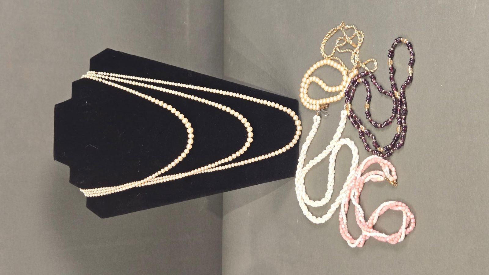 A Collection of Seven Necklaces, Including Pearl and Shell Beads: A collection of seven necklaces, including pearl and shell beads, as indicated by the accompanying label. The lot features a triple-strand necklace of graduated cream-colored spherical beads with a si