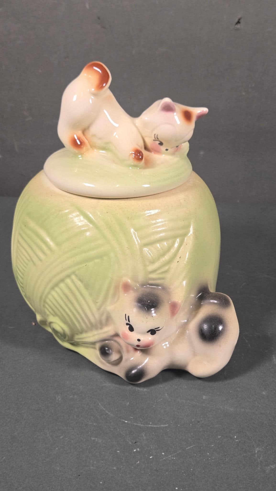 American Bisque Kitten and Yarn Cookie Jar, circa 1940s-1950s: An American Bisque 'Kitten and Yarn' cookie jar, dating from the 1940s-1950s. This glazed ceramic lidded container features a pastel green body textured to resemble a ball of yarn. Two cream-colored c