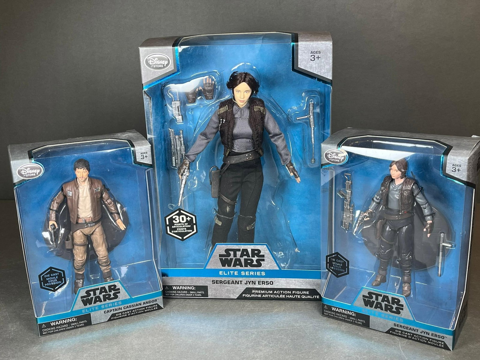 Three Disney Star Wars Elite Series Action Figures, comprising one 10-inch Sergeant Jyn Erso and a: A collection of three factory-sealed Disney Star Wars Elite Series action figures from the *Rogue One* film, presented in their original cardboard boxes with clear plastic windows. The lot includes on