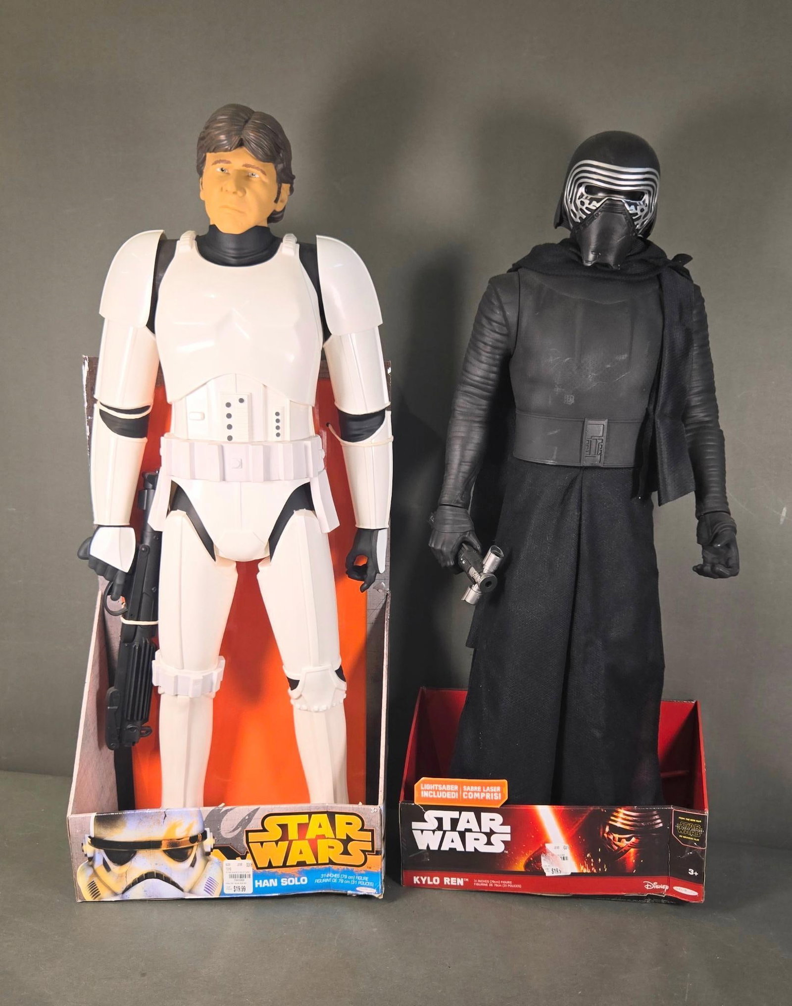 A Pair of Star Wars Jakks Pacific Han Solo Stormtrooper and Kylo Ren Large-Scale Action Figures: A pair of large-scale Star Wars action figures, primarily constructed of plastic with fabric accents, presented in their original, partially open display boxes. The first figure, by Jakks Pacific, dep