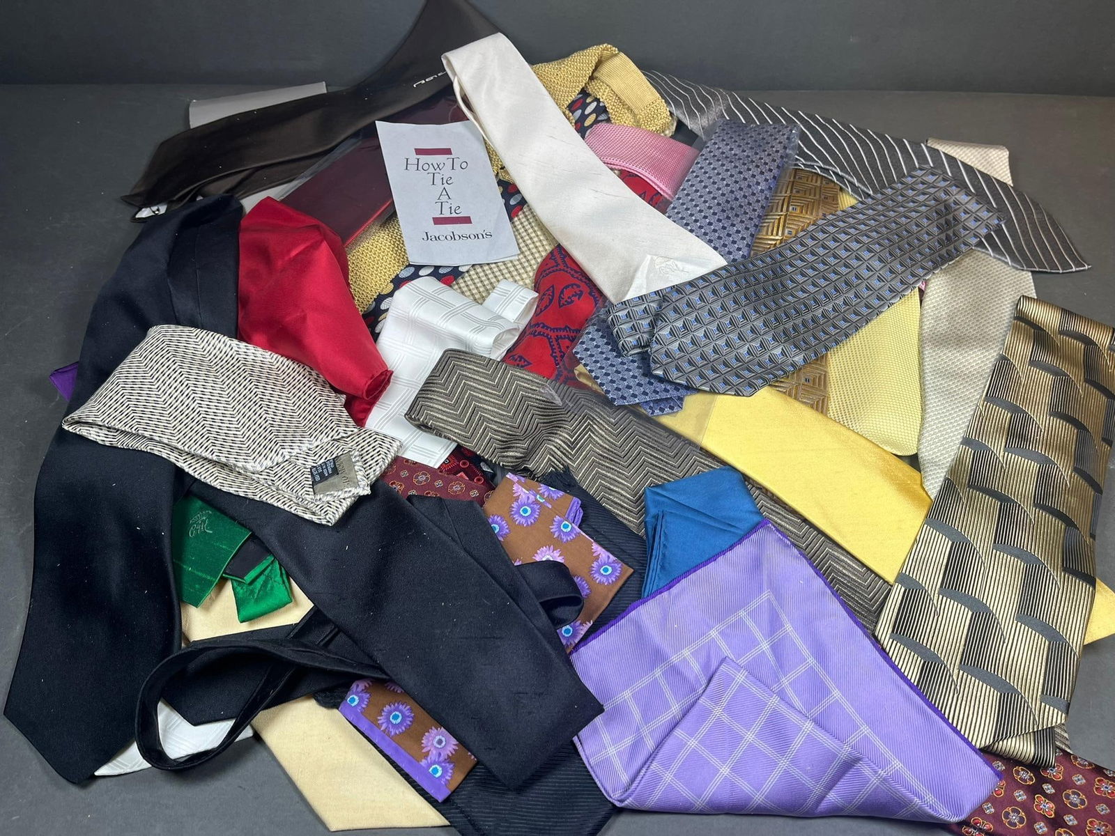 A Collection of Men's Designer and Fine Neckties with Pocket Squares: A substantial collection of men's neckties and several pocket squares. The collection features a wide variety of colors, patterns, textures, including solids, stripes, polka dots, diverse geometric de