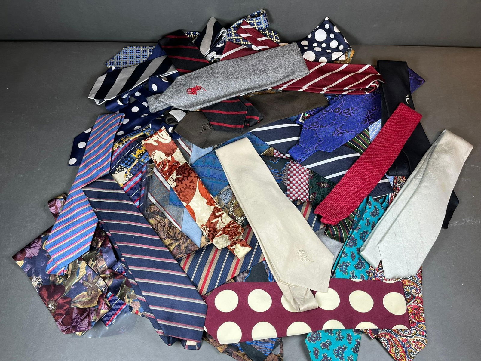 A Collection of Over 100 Men's Neckties, Including Giorgio Armani and Ralph Lauren, in Silk and: A substantial collection of over 100 men's neckties, crafted from various textile materials, likely silk or synthetic blends, and exhibiting a wide array of modern to contemporary styles. The patterns