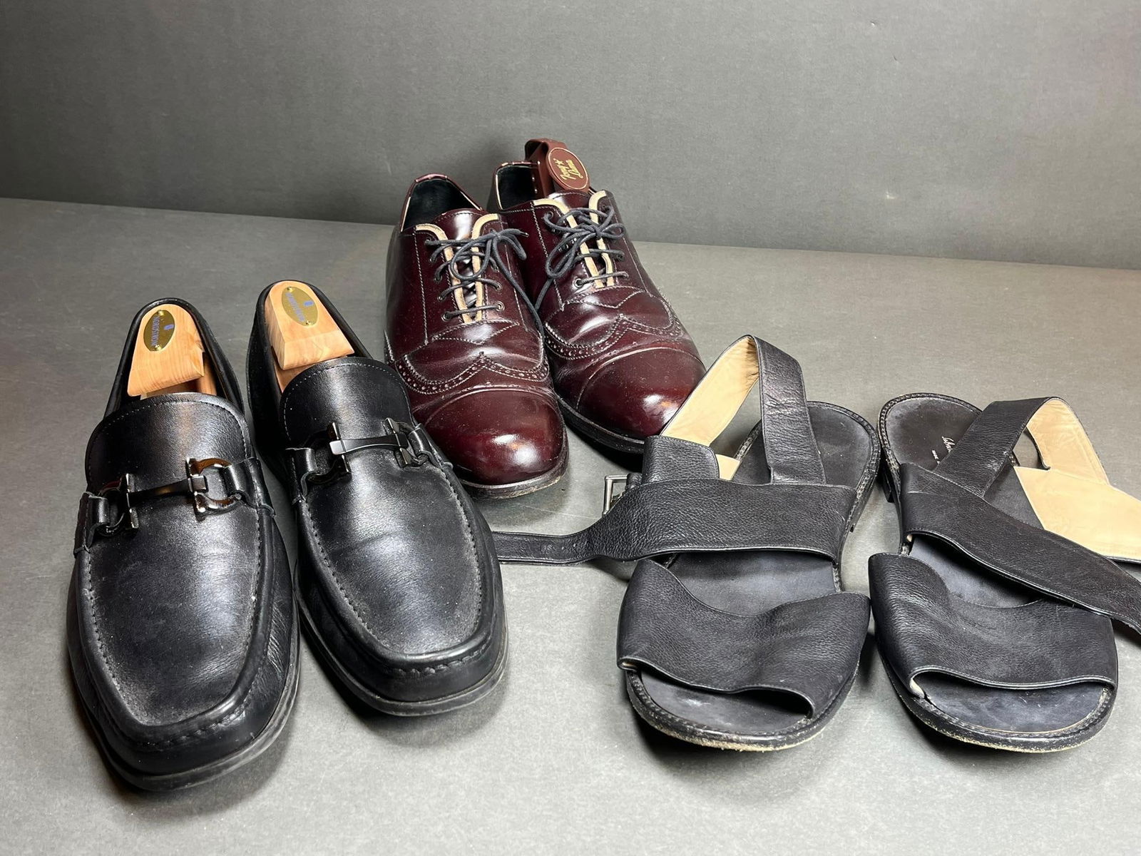Three Pairs of Men's Designer Shoes: Prada Wingtip Brogues and Salvatore Ferragamo Loafers and: This lot comprises three pairs of men's leather shoes from renowned Italian designers. The first pair consists of burgundy (oxblood) polished leather Prada wingtip brogues, featuring decorative perfor