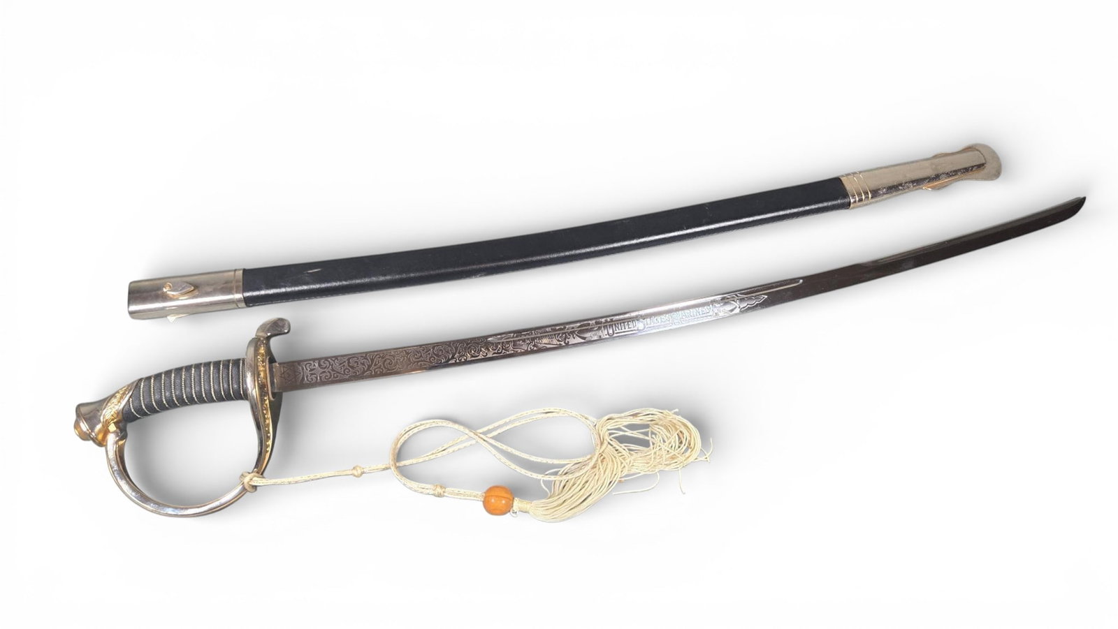 United States Marines Dress Sword with Scabbard and Sword Knot: This lot comprises a military dress sword, its associated scabbard, and a sword knot. The sword features a polished stainless steel blade, visibly marked "440 STAINLESS STEEL" near the hilt. The