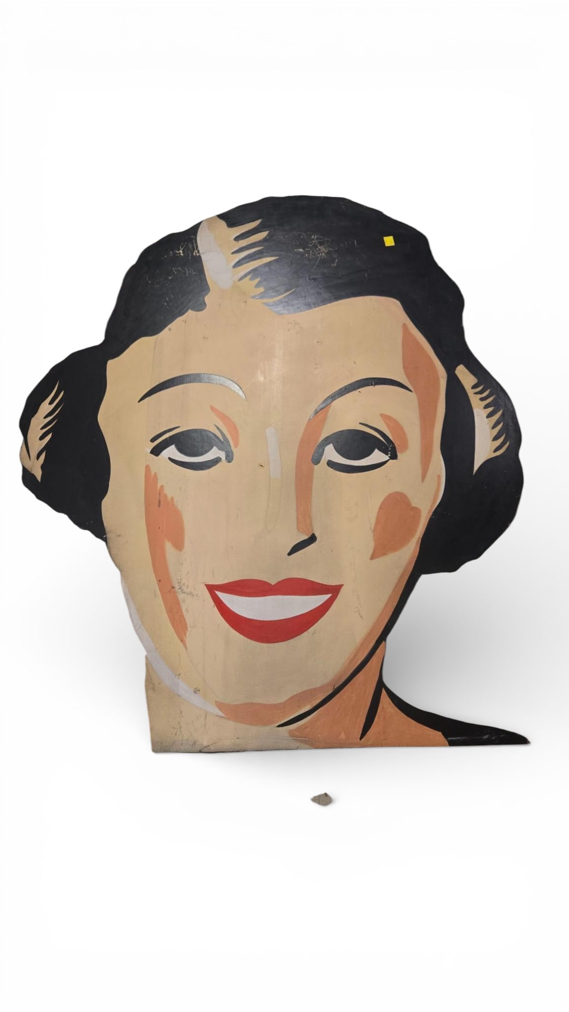 A Mid-20th Century Painted Wooden Cutout Advertising Display Sign: A large, graphically painted wooden cutout display sign, likely dating from the mid-20th century, depicting the smiling head and stylized shoulders of a woman. The sign is executed in a bold,