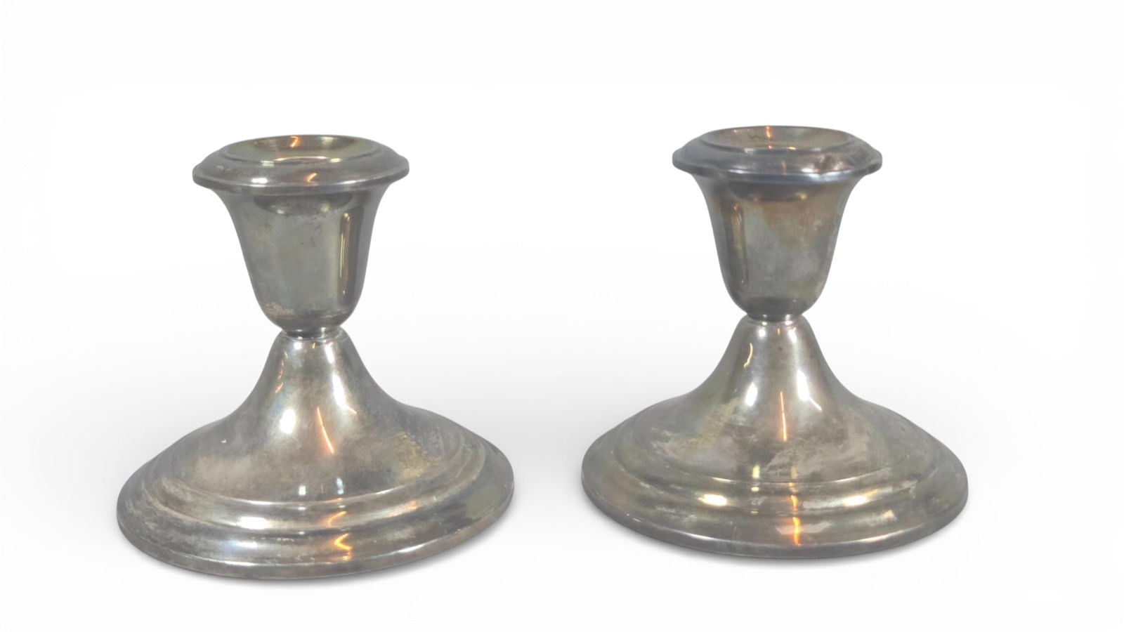 Gorham Sterling Silver Weighted Candlesticks: Weighted candlesticks crafted by the Gorham Manufacturing Company. The design is traditional and utilitarian, featuring a low, wide circular base that tapers rapidly inward to a narrow standard, toppe