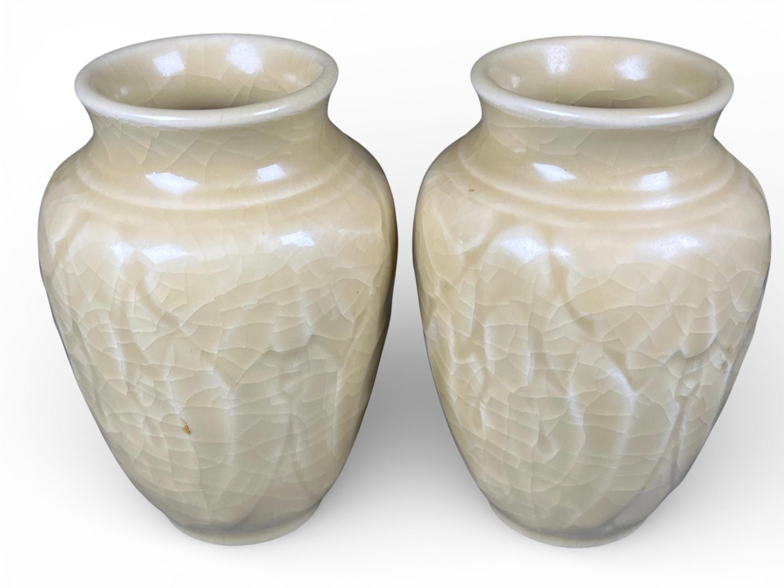Rookwood Pottery Vases in Pale Crackle Glaze: Ceramic vases attributed to Rookwood Pottery. Each vase features a squat, globular body rising to a short, slightly flared rim. The vessels are covered in a high-gloss, pale cream or ivory-colored cra