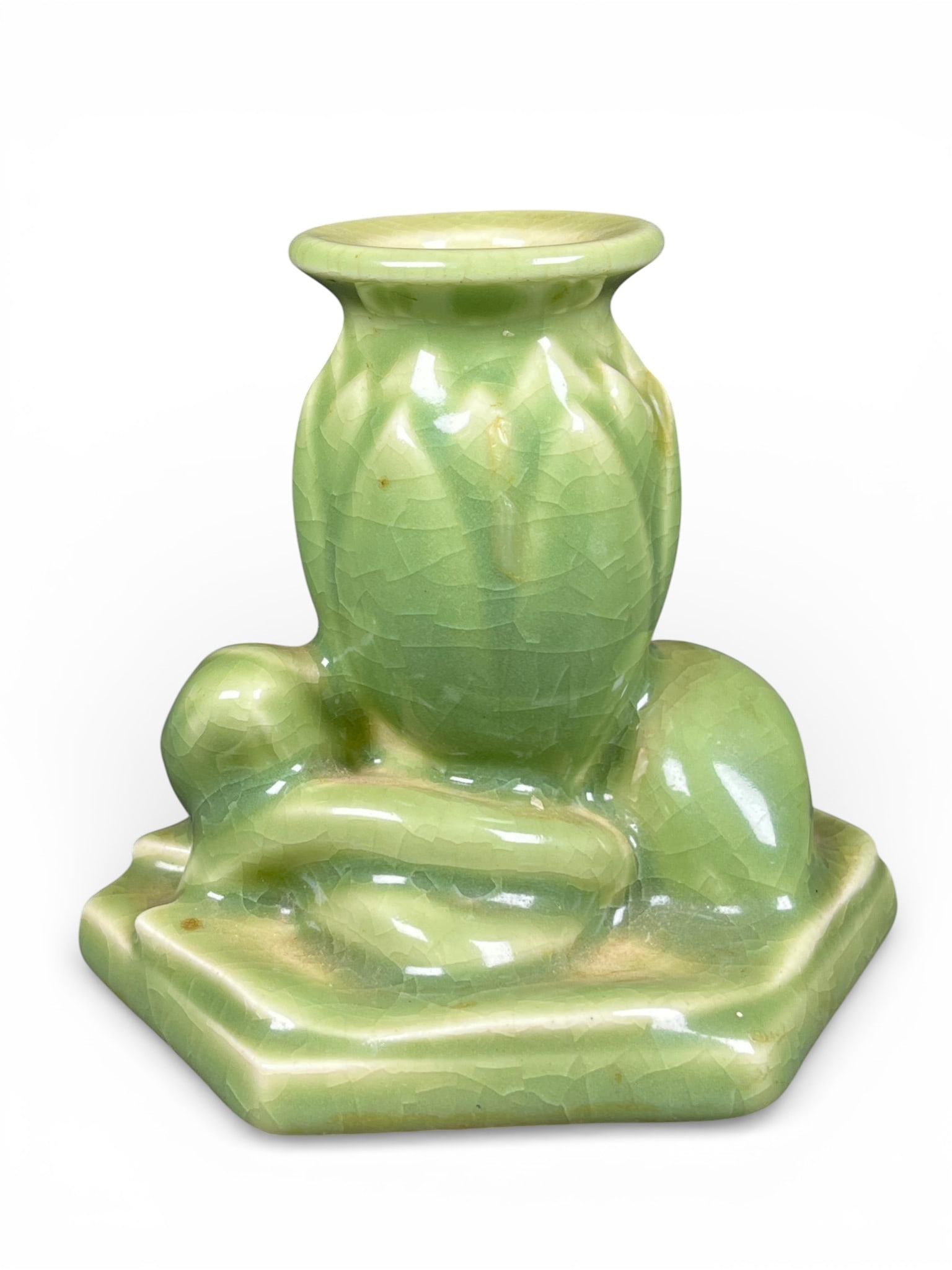 Rookwood Miniature Green Celadon Crackle Glaze Ceramic Lotus Bud Vessel or Candle Holder: A single miniature ceramic vessel executed in a pale celadon green glossy crackle glaze. The object is constructed on a low, hexagonal platform base. The central element is a vertically ribbed vessel,