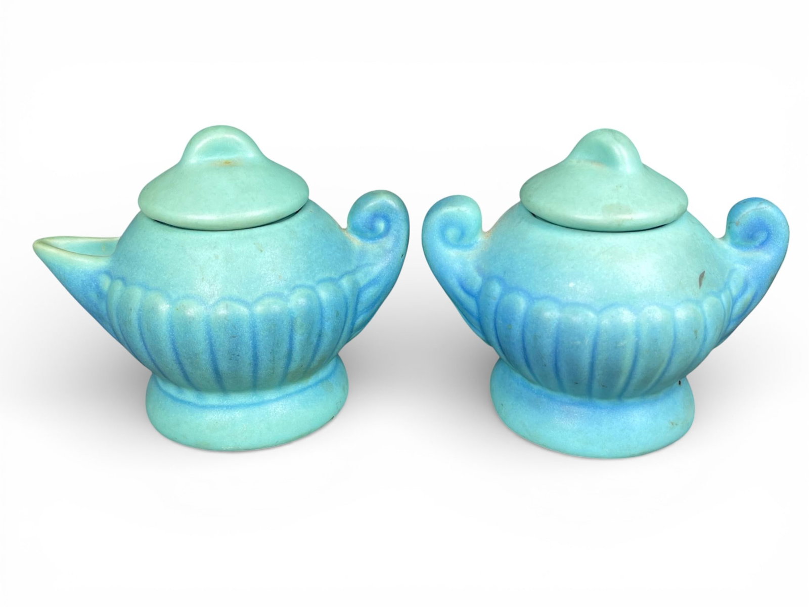Van Briggle Art Pottery Aladdin Lamp Creamer and Sugar Bowls: Van Briggle Art Pottery vessels, modeled in the form of stylized Aladdin or genie lamps, designed to function as a creamer and an open sugar bowl set. The ceramic bodies are finished in a characterist