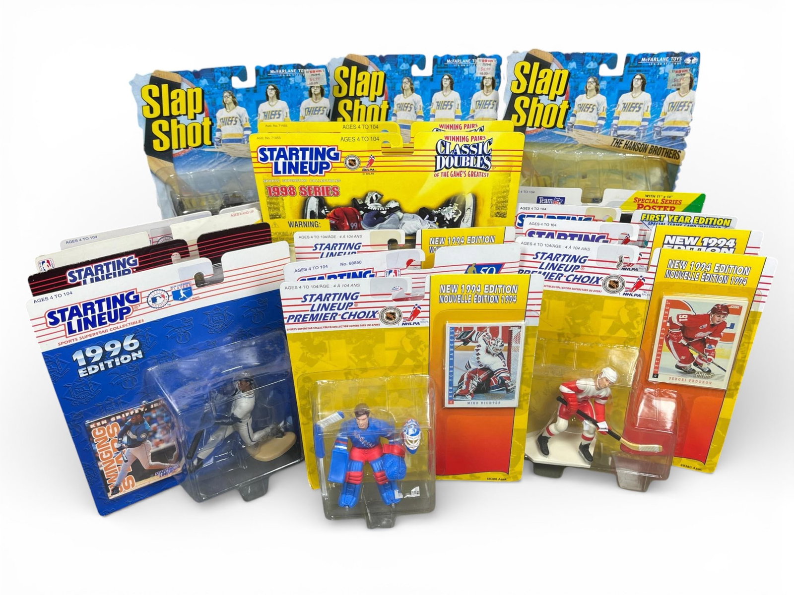 A Collection of Kenner Starting Lineup and McFarlane Toys Slap Shot Action Figures: A collection of vintage sports action figures, primarily from the "Starting Lineup" series by Kenner and "Slap Shot" figures by McFarlane Toys. All figures are presented in their original,