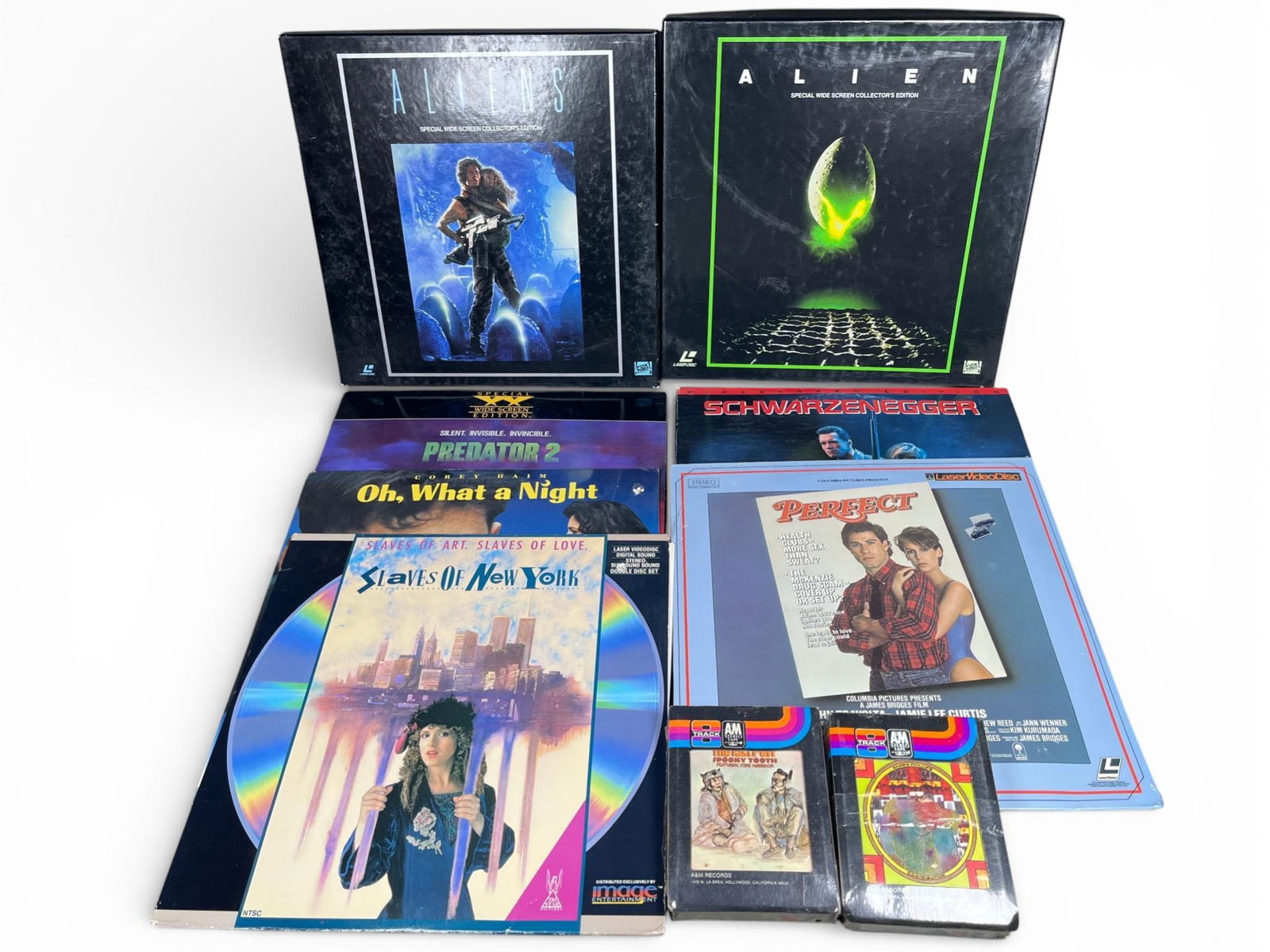 A Collection of Late 20th Century LaserDiscs and 8-Track Tapes: A collection of vintage media items, primarily from the late 20th century, comprising LaserDisc titles and 8-track tape cartridges. Burns in-house shipping is available. Pick up is Friday, Jan. 30 fro