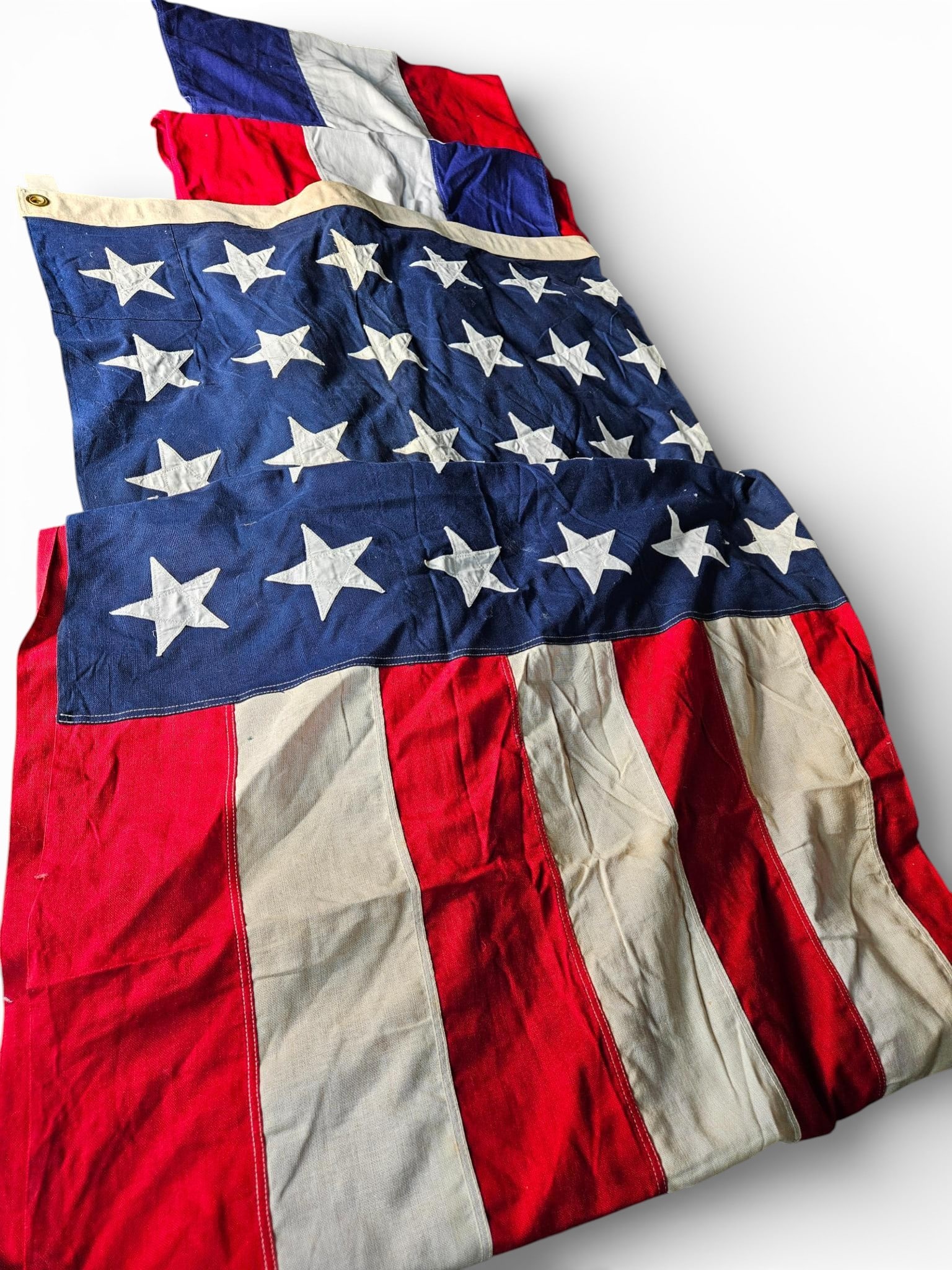 A group of Vintage Patriotic Textiles Large 48-Star USA Flag and Lengths of Tri-Color Bunting: This collection comprises vintage patriotic textile items, including a large USA flag and large pieces of bunting. The primary item is a large American flag featuring the 48-star configuration, consis
