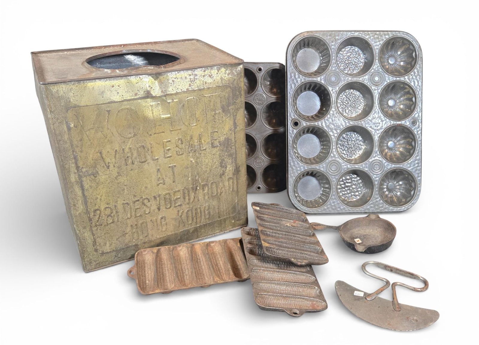 Vintage Kitchenware Items including Cast Iron Corn Stick Pans: A group of vintage domestic and kitchen items, primarily comprising cast iron and tinware. The collection includes metal muffin pans identified through consensus as Ekco Ovenex Starburst bakeware,