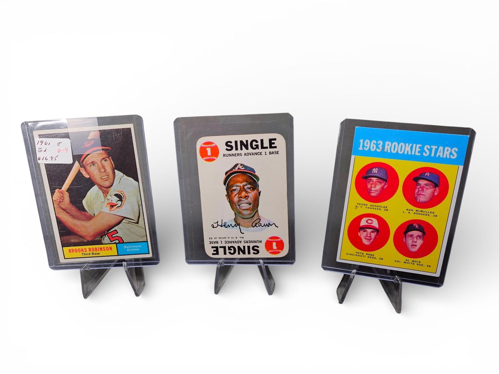 Vintage Topps Baseball Cards1968 Topps Game Aaron #4, Brooks Robinson, and 1963 Rookie Stars Pete: A group of vintage baseball trading cards and game inserts printed on paper stock in the U.S.A., encapsulated in clear plastic toploaders. The collection includes distinct items. The first item is a 1