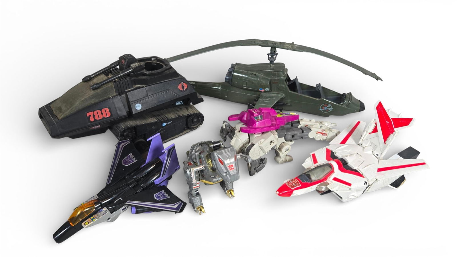 A group of Transformers and G.I. Joe Action Figure Vehicles and Transforming Toys: A group of molded plastic action figures and vehicles spanning the G.I. Joe and Transformers franchises, likely originating from the 1980s through the 1990s and possibly including later collaborative
