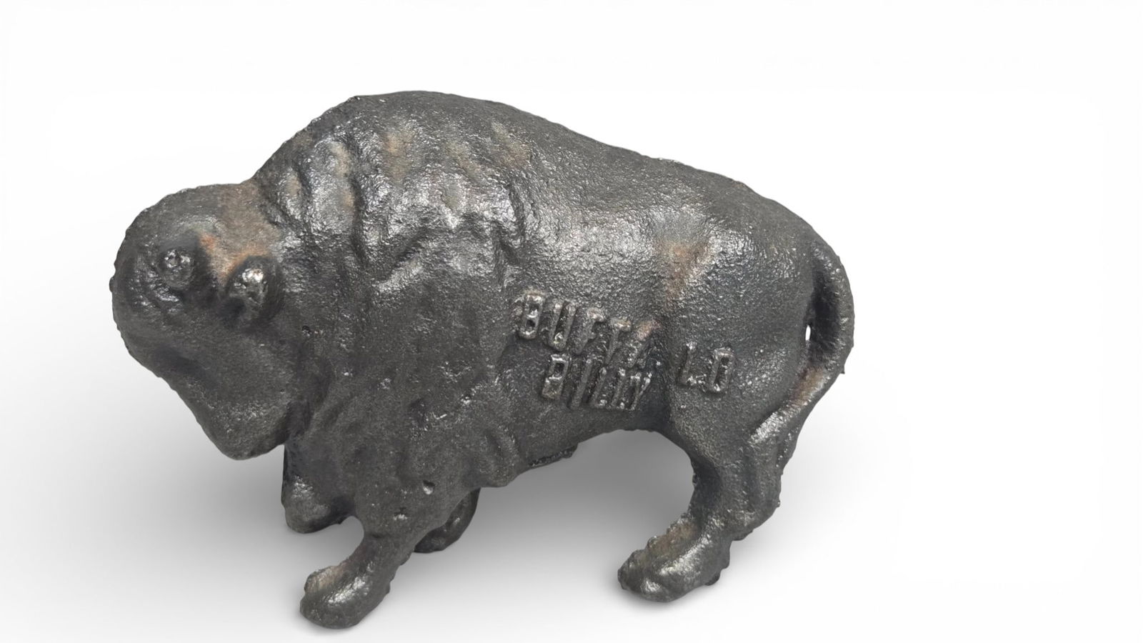 Antique Cast Iron Figural Still Bank, Buffalo Billy Bison Model: A cast iron figural still bank modeled in the representation of a standing American Bison. The bank is constructed from bolted halves joined along a central vertical seam, which incorporates a coin