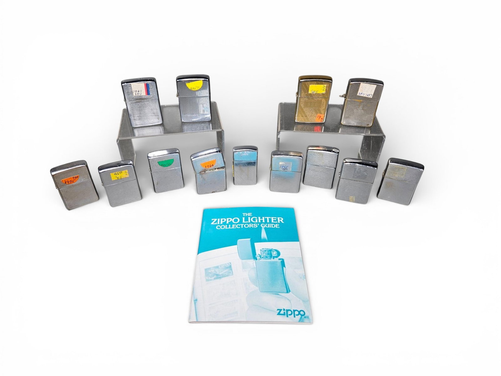 Vintage Zippo Windproof Lighters and Collector's Guide: This collection features an assortment of vintage Zippo windproof lighters accompanied by a reference pamphlet titled The Zippo Lighter Collectors' Guide. The lighters are manufactured from various ma