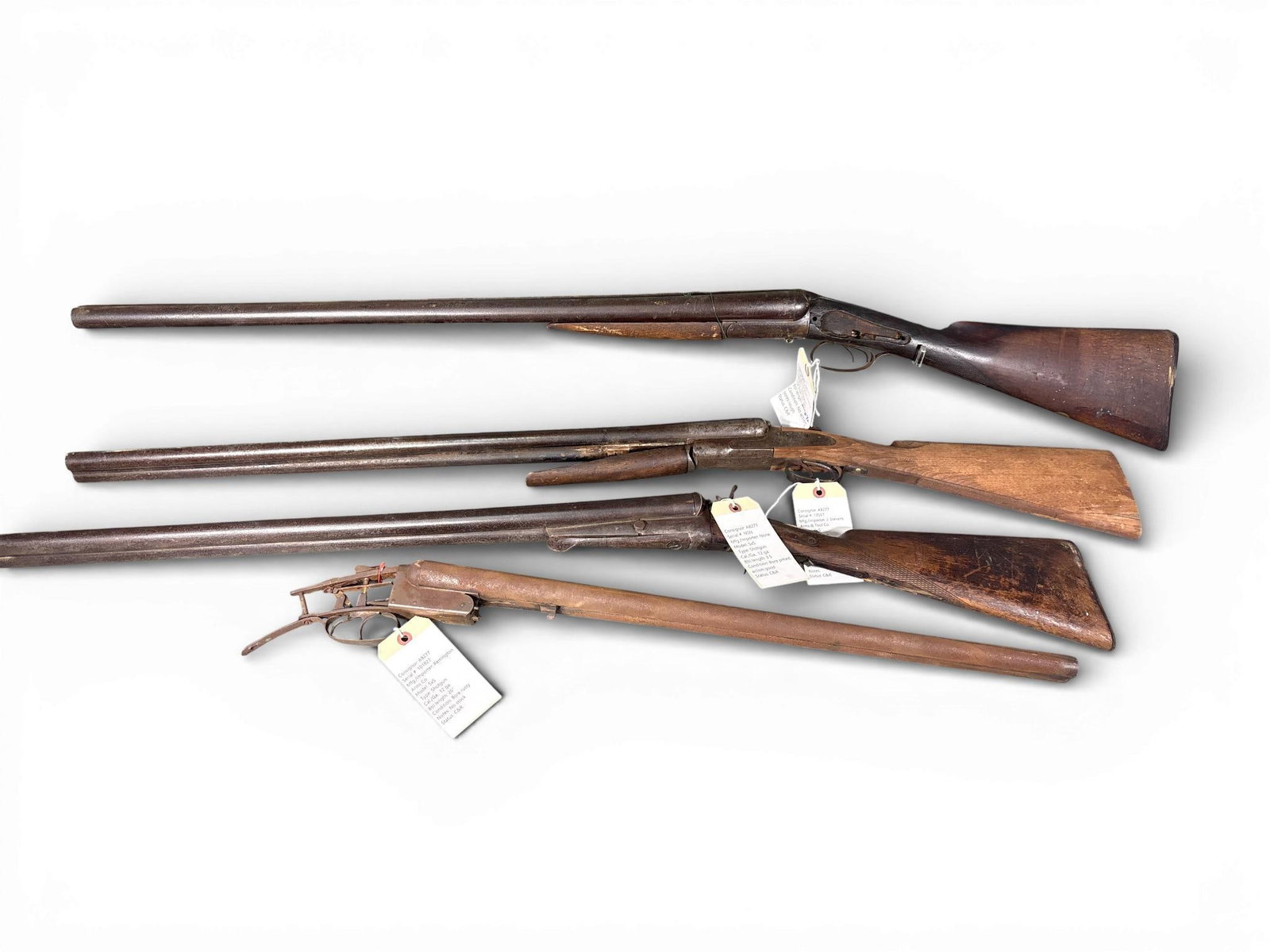 ** Four Old Wall Hanger Double Barrel Shotguns: This collection consists of four old wall hanger double barrel shotguns in side-by-side configuration. The group is primarily composed of steel and wood components from manufacturers including