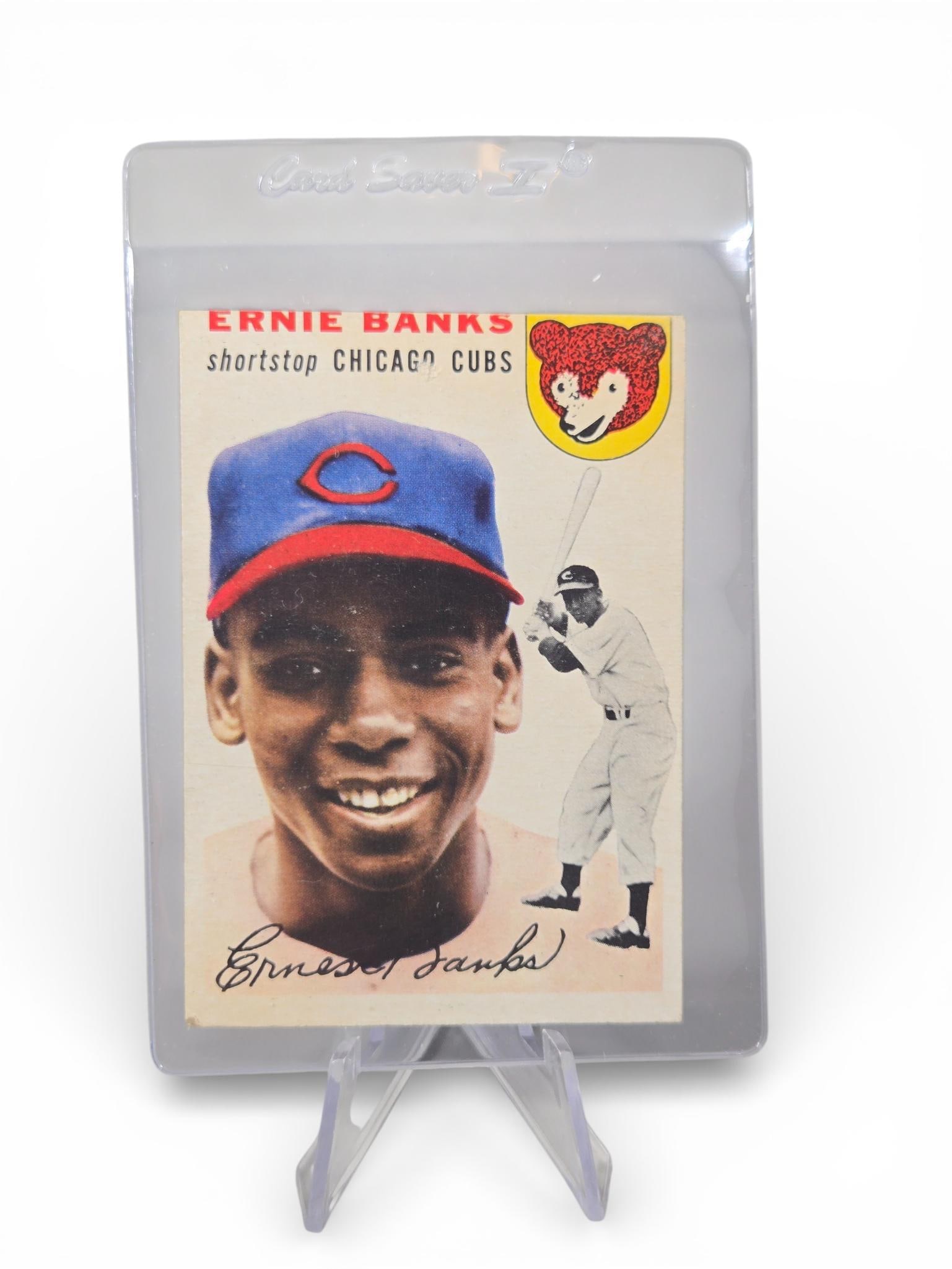 1954 Topps Ernie Banks Rookie Card #94: A 1954 Topps Ernie Banks rookie card, number 94, for the Chicago Cubs. The card features a dual-image design on the front with a color portrait of Banks, a background action illustration, the team