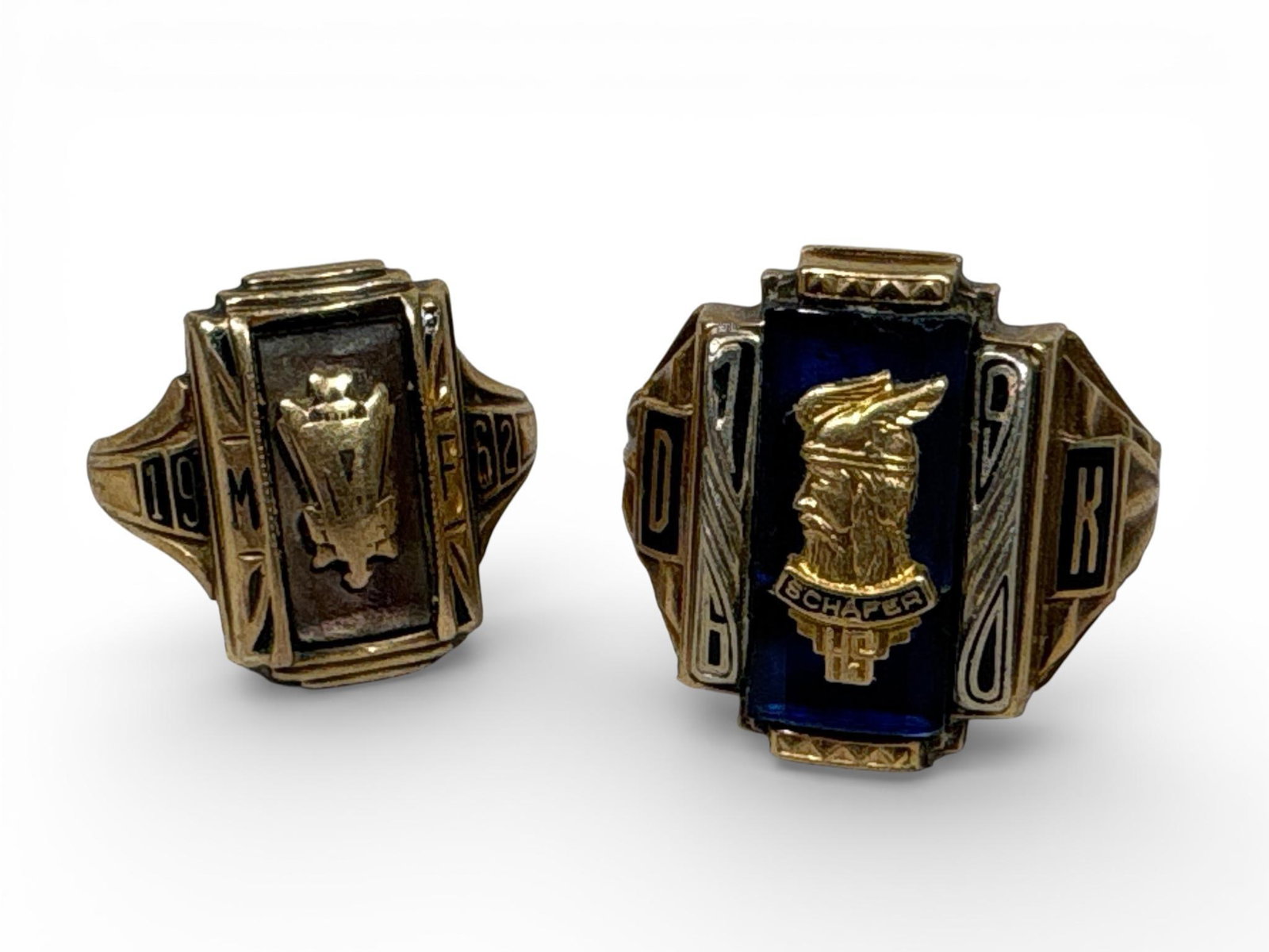 A Pair of Vintage 10k Yellow Gold Class Rings 13.08 grams: A pair of vintage 10k yellow gold class rings dating to the early 1960s. The first ring features a dark-toned rectangular inset with a central relief-molded crest, with shoulders dated 1962 and featur