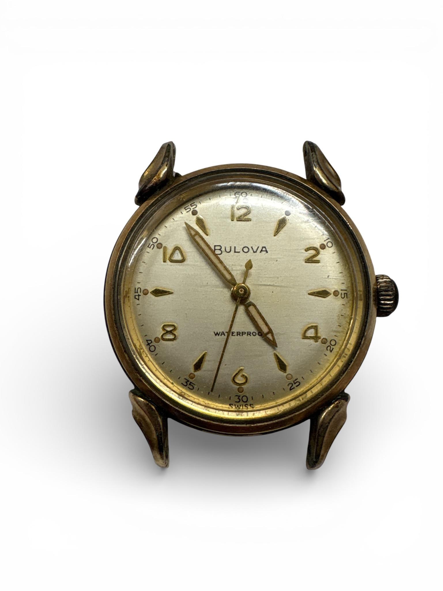 A 1959 Bulova Clipper 10K Rolled Gold Plate Wristwatch Head: This Bulova Clipper wristwatch head features a round 10K rolled gold plate bezel with a stainless steel screw-down case back. The case back is stamped with the L9 date code, signifying a manufacture