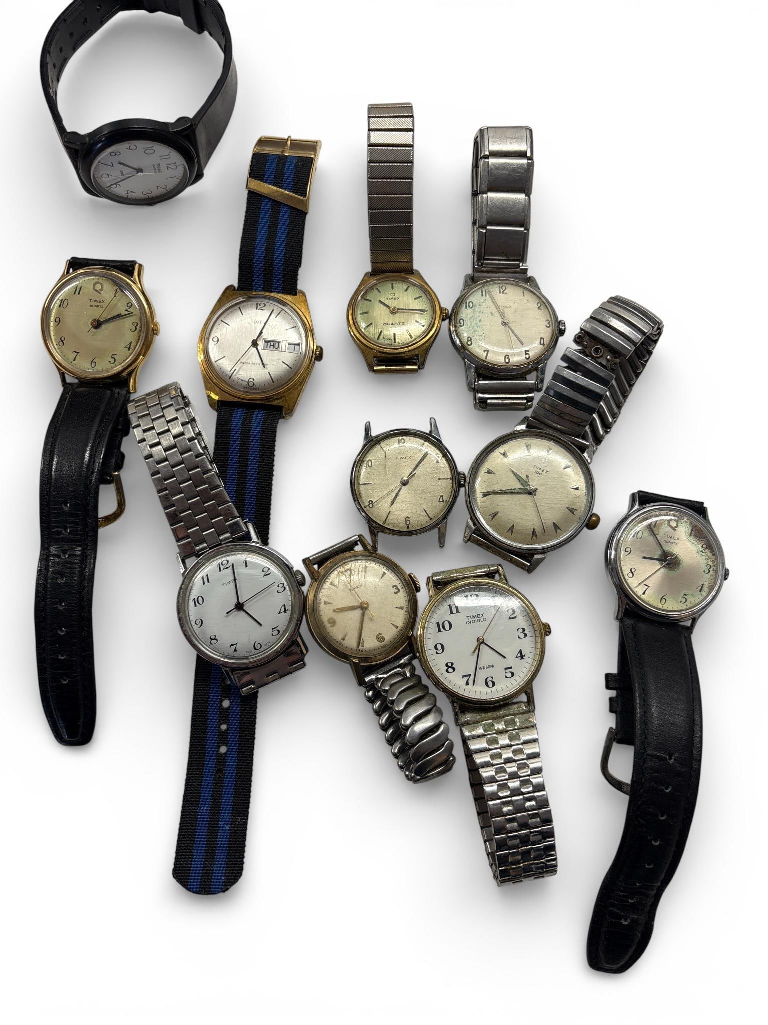 A Collection of Timex Wristwatches: A collection of Timex wristwatches featuring a variety of vintage and contemporary designs. The assortment includes metal cases in gold-toned and silver-toned finishes, alongside a black plastic