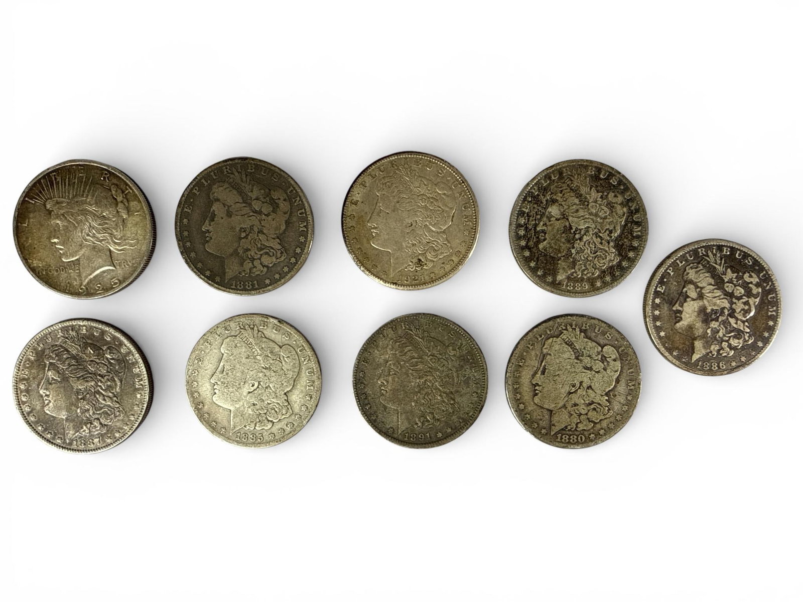 A Group of United States Morgan and Peace Silver Dollars: A group of United States silver dollar coins comprising Morgan and Peace dollar types. The collection includes Morgan dollars with dates including 1880, 1881, 1885, 1886, 1887, 1889, 1891, and 1921, a