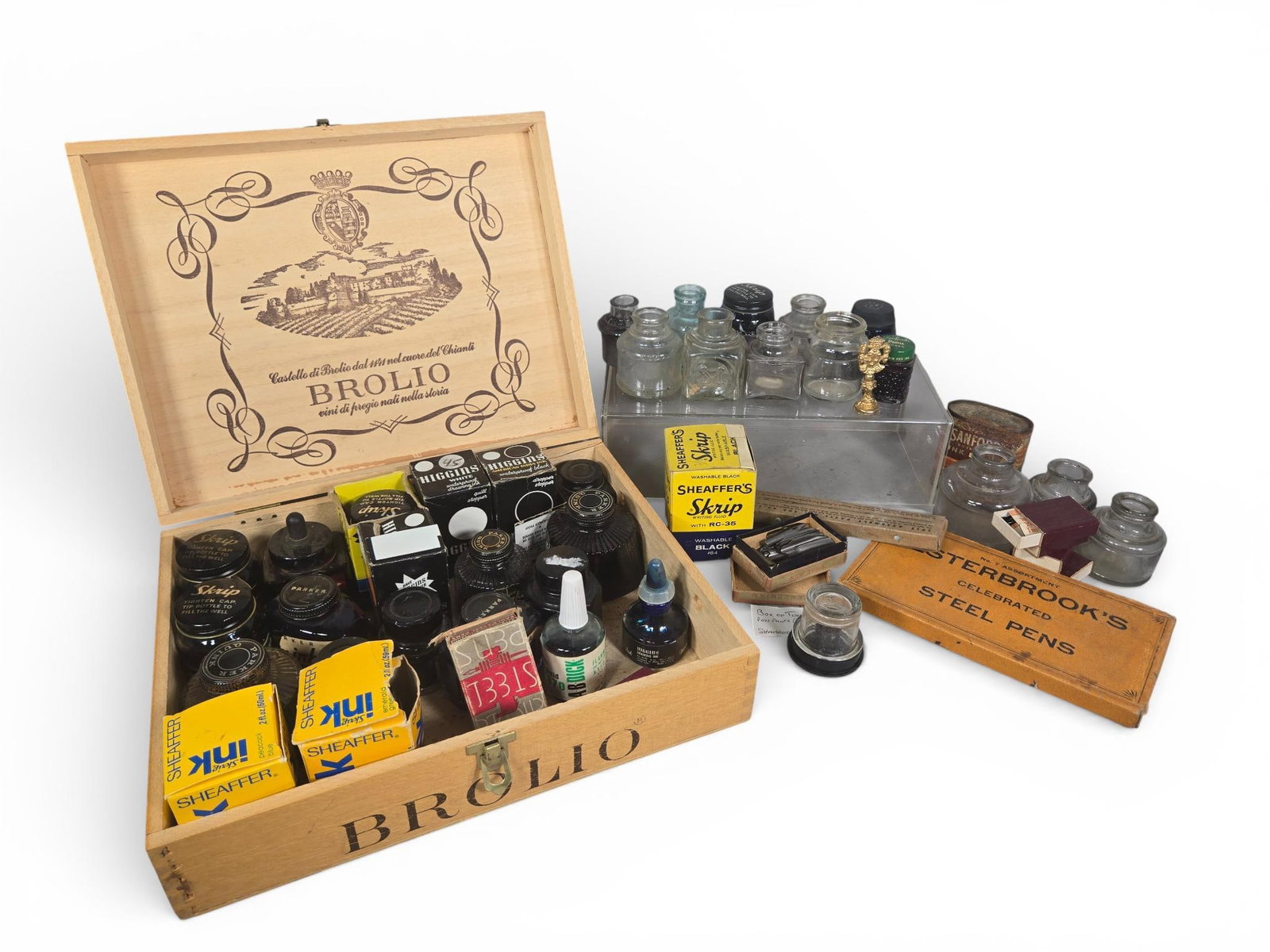 An Assortment of Vintage Writing and Calligraphy Supplies in a Brolio Castello di Brolio Wooden: This collection of vintage writing and calligraphy supplies is housed in a repurposed wooden wine crate from Barone Ricasoli, marked Brolio Castello di Brolio. The assortment includes various glass in