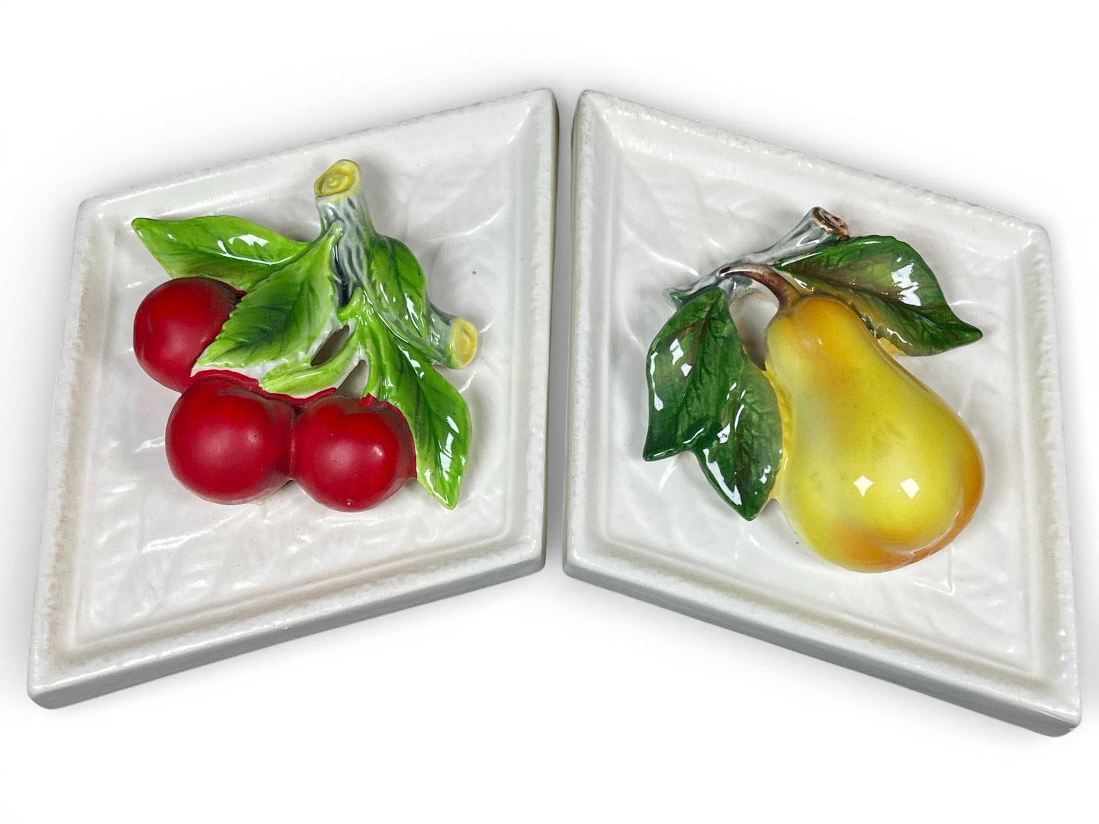 Pair of Lefton Mid-Century Modern Diamond Ceramic Fruit Wall Plaques: A pair of mid-century modern ceramic wall plaques attributed to Lefton. These diamond-shaped pieces are crafted from a molded earthenware body featuring fruit in high relief (bas-relief). One plaque d