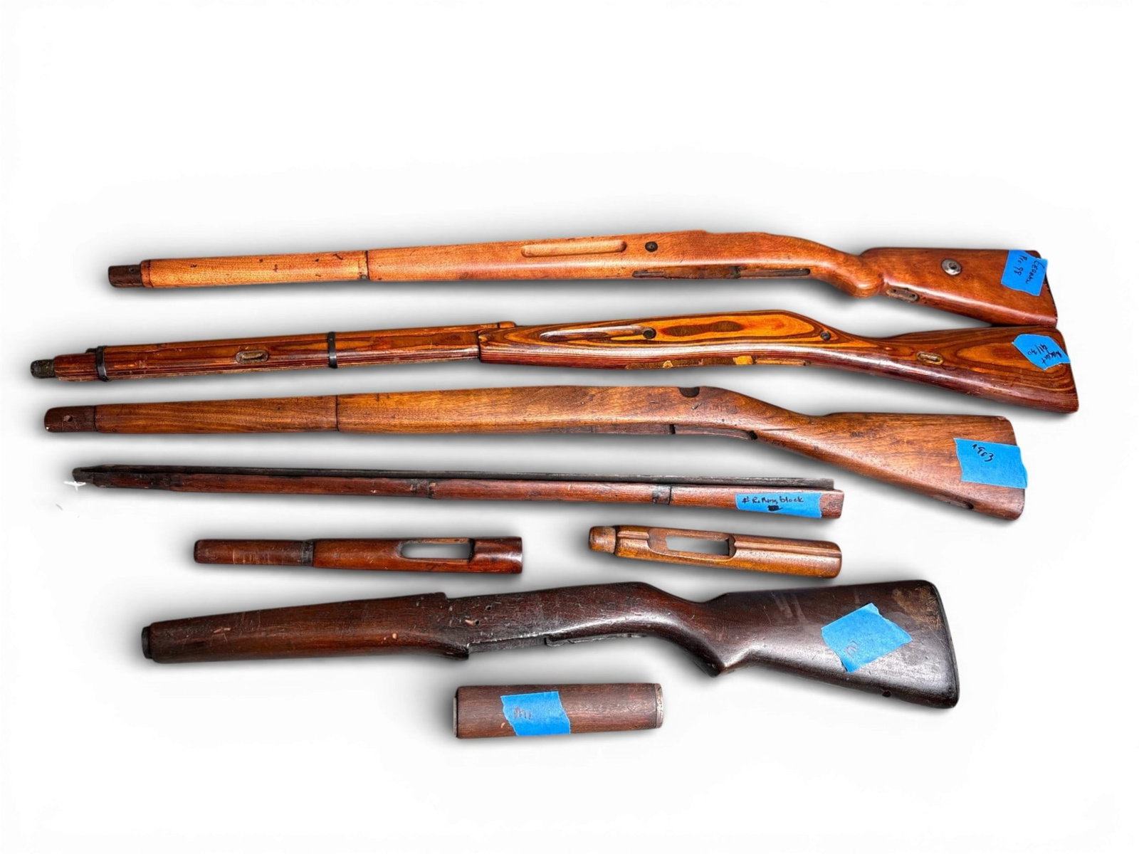A Collection of Military Rifle Stocks Including M1, Remington Rolling Block, 1903 Springfield,: This collection consists of multiple vintage and antique military rifle wooden stocks and handguard components, dating from the late 19th through the mid-20th centuries. The assortment includes