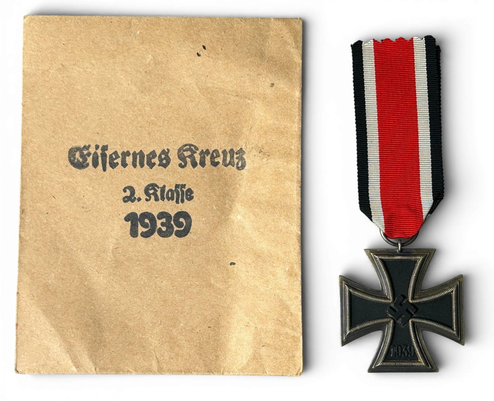 WWII Nazi German 2nd Class Iron Cross with Envelope: German World War II 2nd Class Iron Cross decoration with envelope. The round suspension ring is maker marked ‘L/15’. Includes the presentation machine embroidered cloth woven cotton ribbon. Three