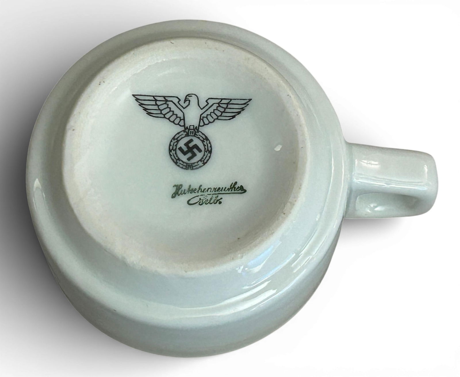 WWII Nazi German Wehrmacht - Heer Porcelain Coffee Cup by Hutschenreuther Selb: World War II German Wehrmacht - Heer porcelain coffee cup. The cup is plain on the obverse. The underside has an eagle clutching a wreathed swastika above the maker's mark Hutschenreuther Selb. The cu