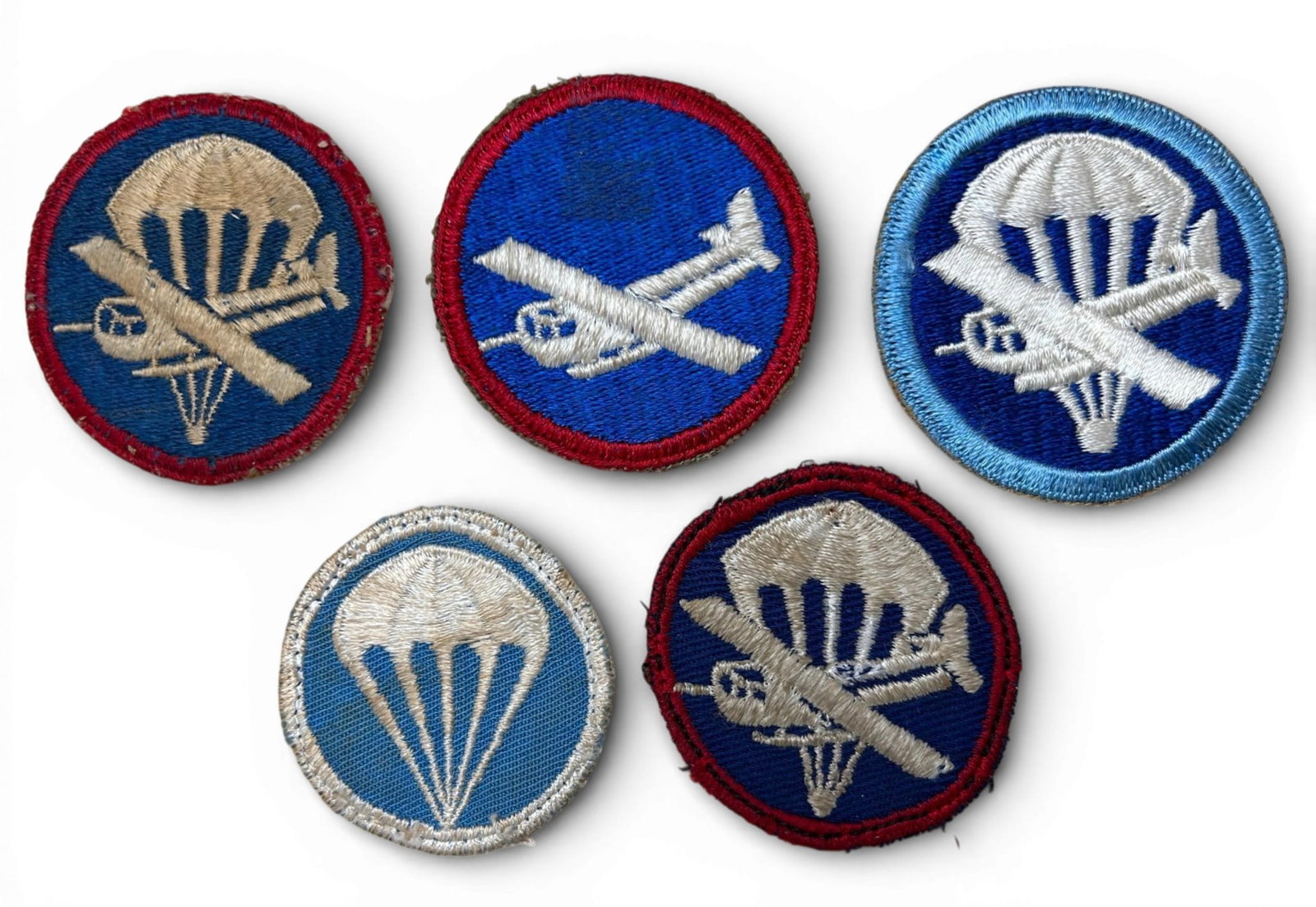 WWII Airborne Paratrooper & Glider Cap Badge Lot: World War Two airborne paratrooper cap badge lot (5) including glider patches. One patch was removed from a cap and one from a scrapbook. Two of these patches have cheesecloth backing. Pick up is Sund