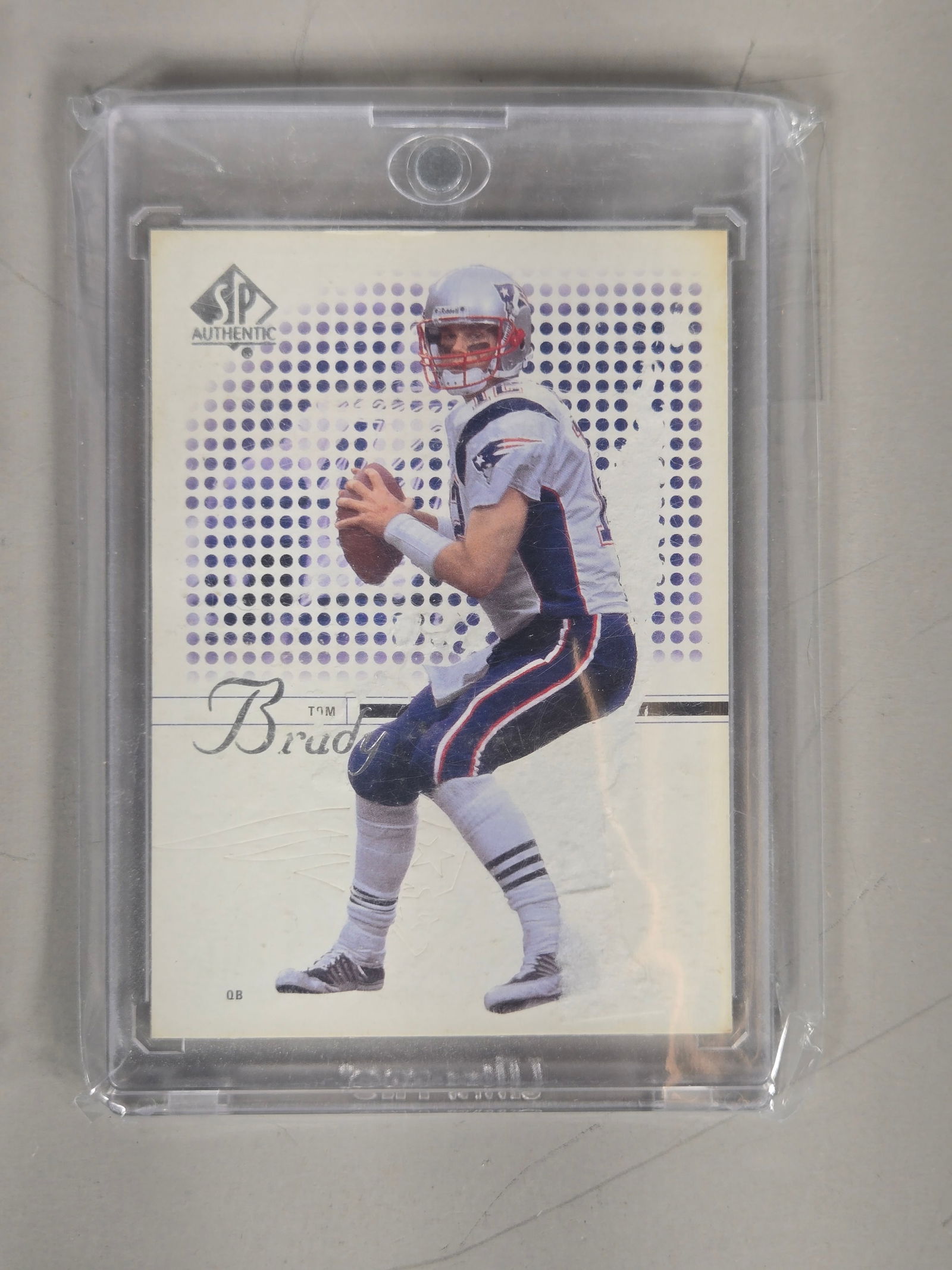 A Collection of American Football Trading Cards Including 2002 SP Authentic Tom Brady: A collection of American football trading cards featuring a mix of vintage and modern issues. The group is highlighted by a 2002 SP Authentic Tom Brady card. Modern examples include a Panini Spectra E