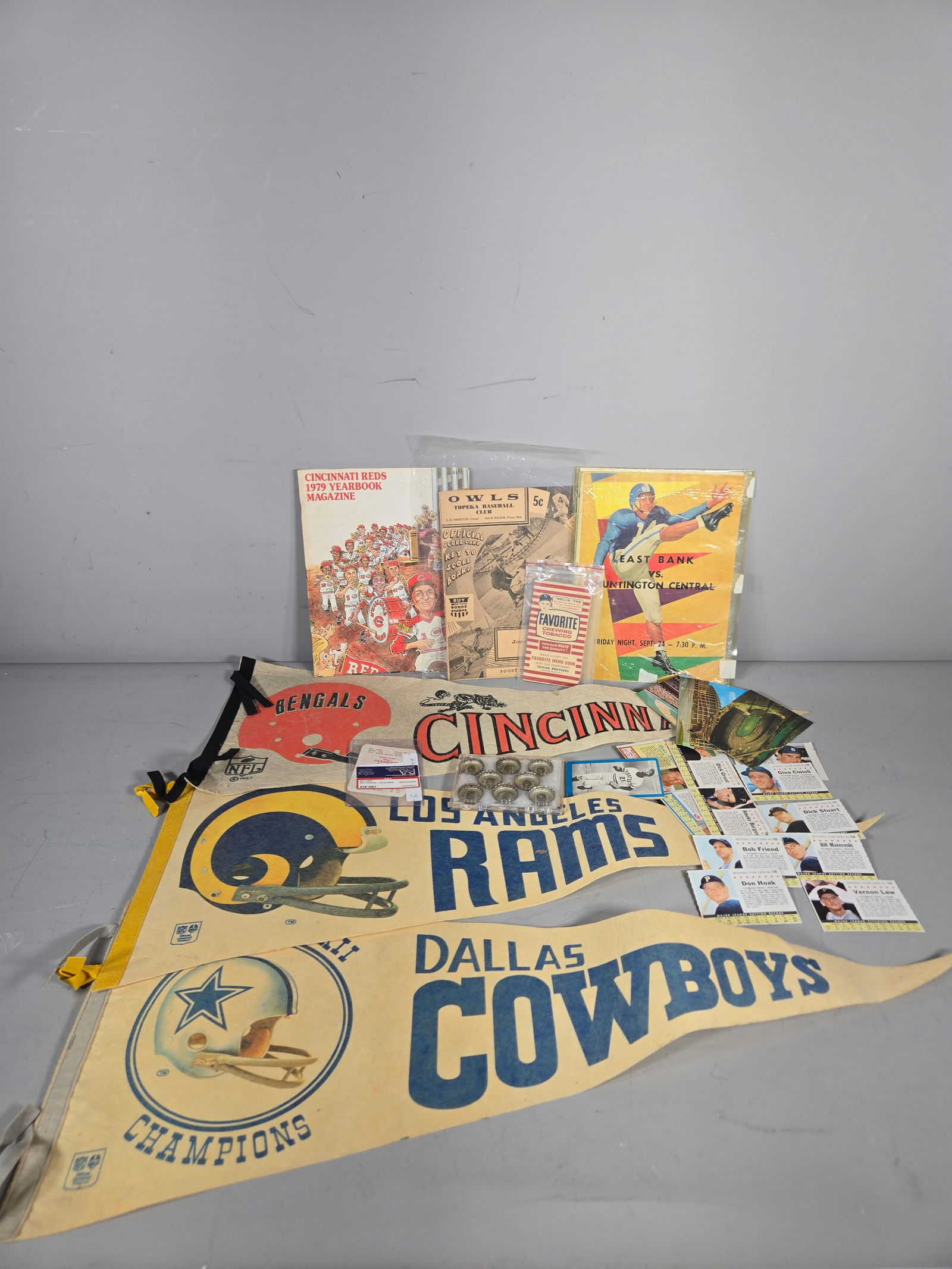 A Collection of Vintage Sports Memorabilia and Ephemera featuring NFL Pennants and Baseball Cards: This collection features several full-size felt pennants, including a Dallas Cowboys Super Bowl XII Champions pennant, a 1967 Cincinnati Bengals pennant, and a Los Angeles Rams pennant. Printed materi
