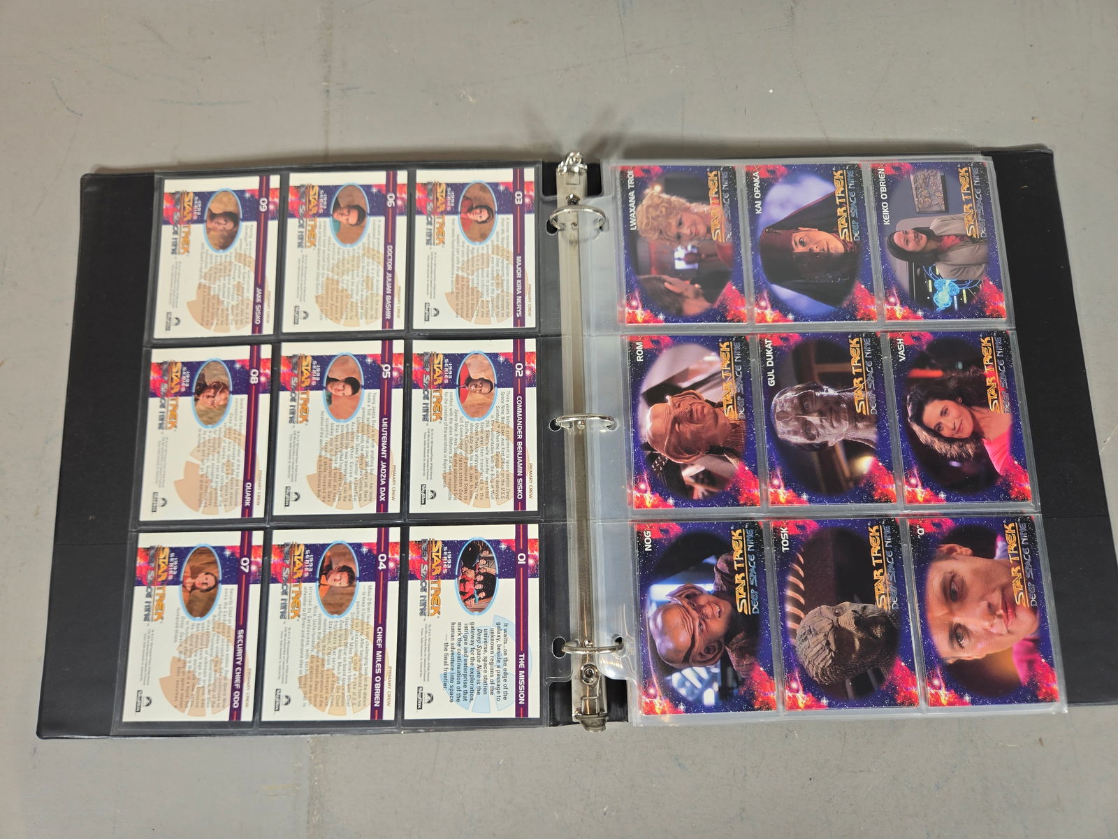 A Collection of 1993 SkyBox Star Trek Deep Space Nine Trading Cards: A collection of 1993 SkyBox Star Trek: Deep Space Nine trading cards presented in a black three-ring binder with clear plastic pocket pages. The assortment includes character profiles for Commander Be