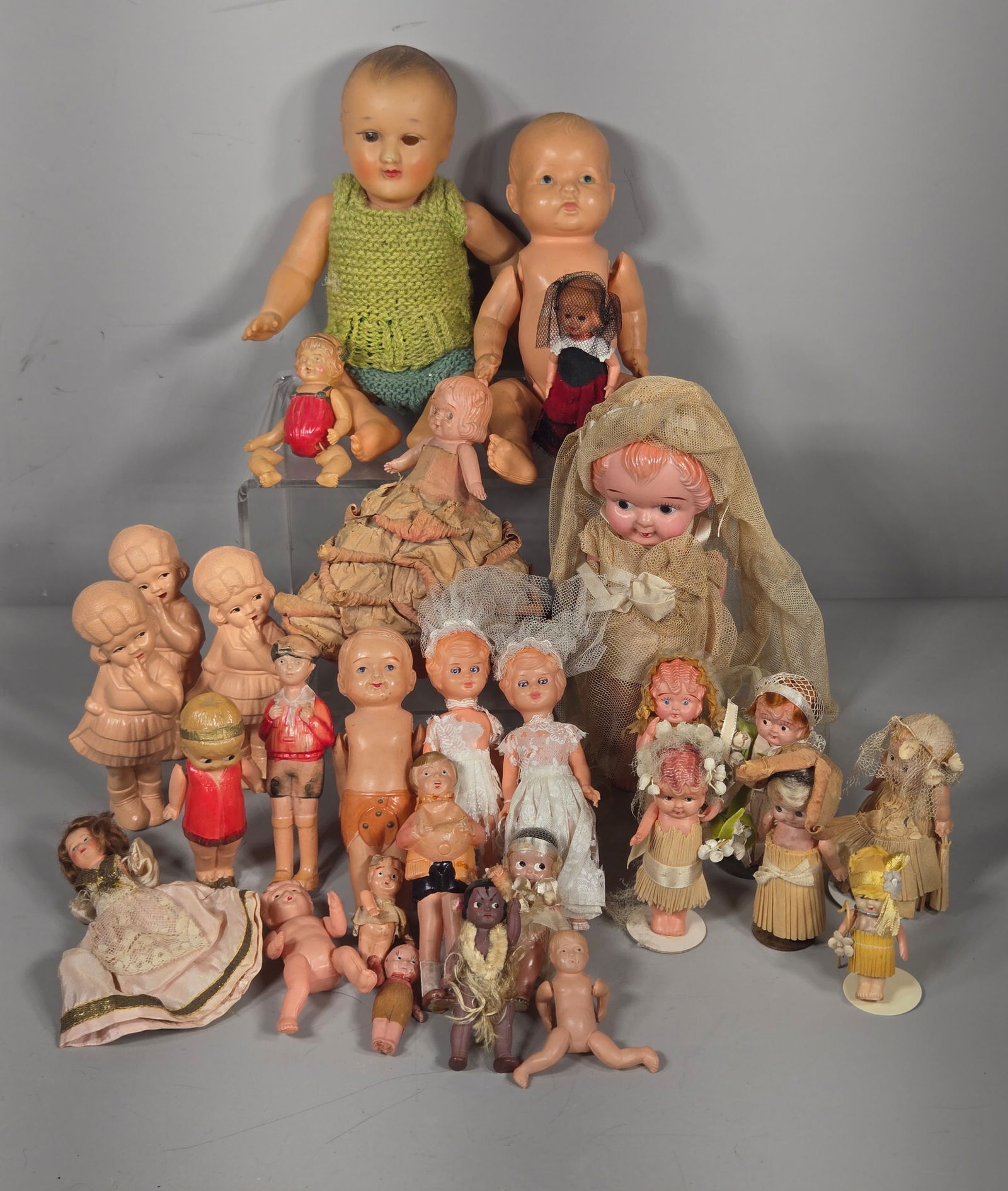 A Collection of Mid-20th Century Celluloid and Hard Plastic Dolls: This collection features an assortment of mid-20th century dolls and figurines primarily constructed from celluloid and hard plastic. The group includes various styles such as Kewpie-style figures, jo