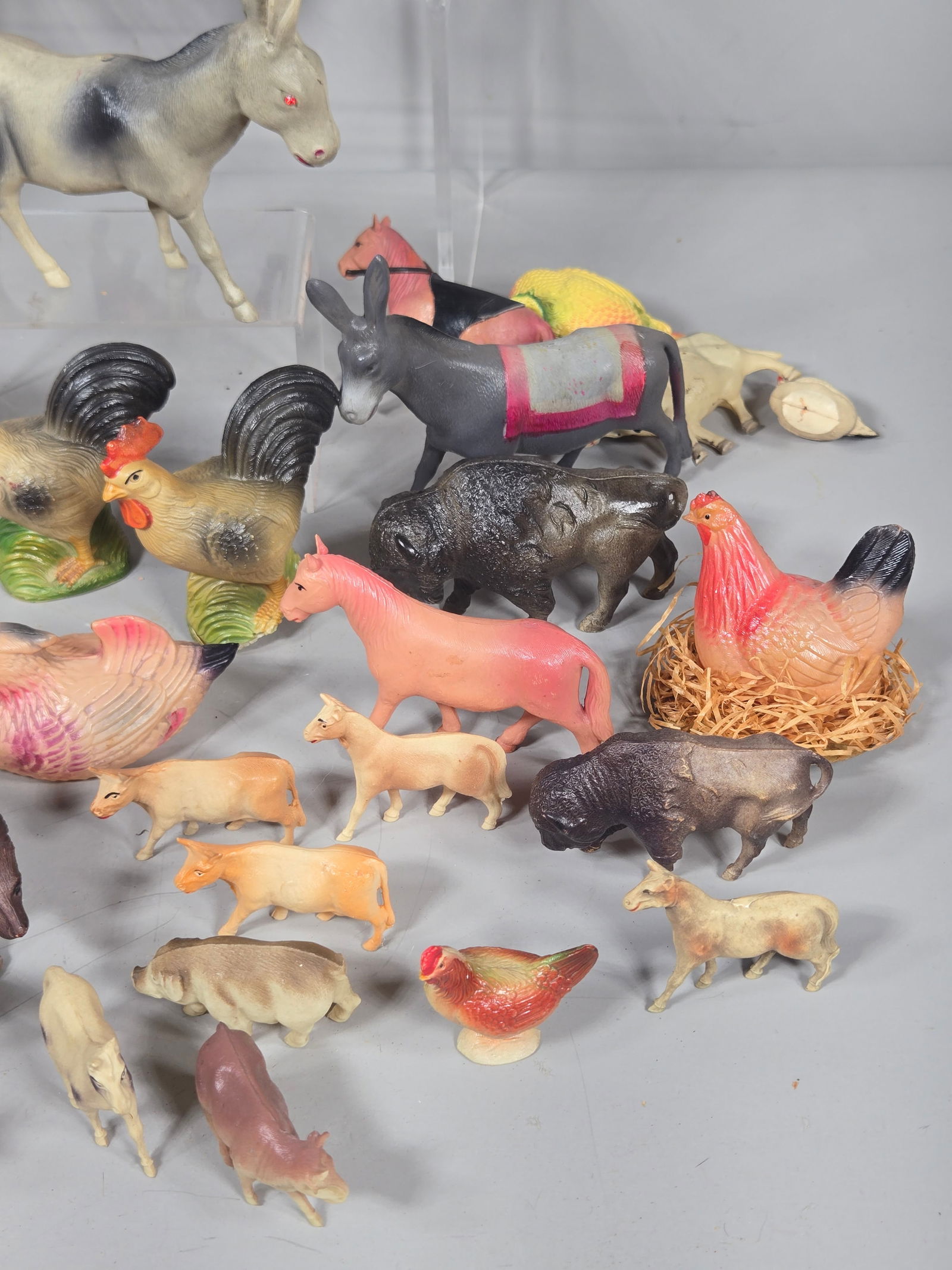 A Collection of Vintage Celluloid and Molded Plastic Toy Animals: This collection consists of vintage celluloid and molded plastic toy animal figurines. The assortment primarily features farm animals such as roosters, chickens, donkeys, horses, cows, and a turkey, a
