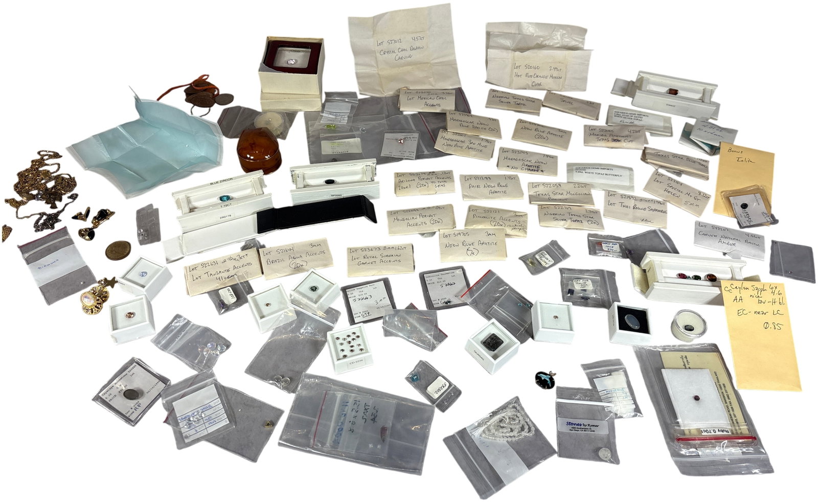 An Extensive Estate Collection of Loose Gemstones, Costume Jewelry, and Coins: This estate collection features an extensive assortment of loose faceted and carved gemstones, costume jewelry, and coins, many accompanied by original supplier packaging and identification notes. The