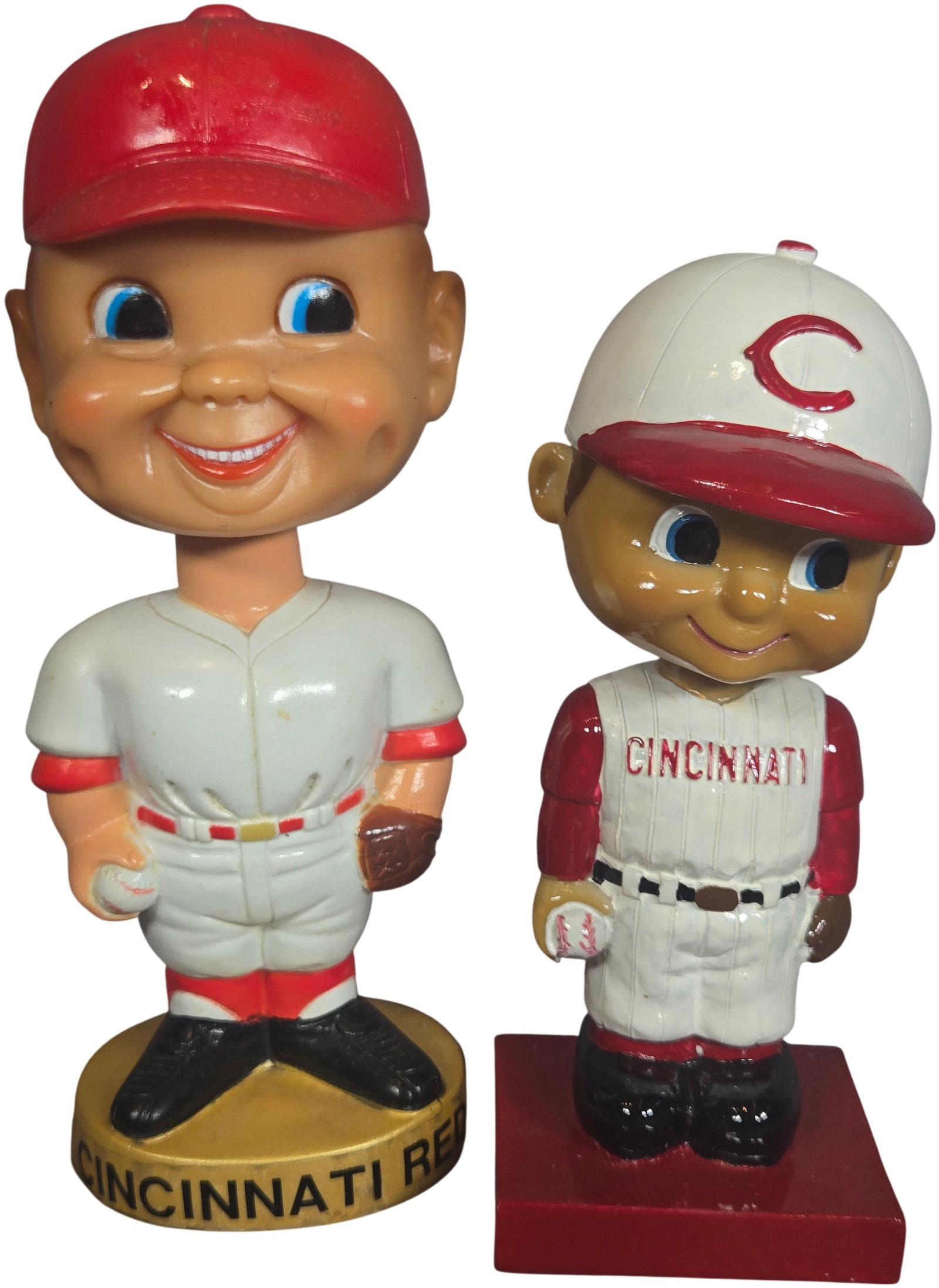 A Pair of Vintage Cincinnati Reds Baseball Bobbleheads: A pair of vintage-style baseball bobbleheads, commonly referred to as nodders, representing the Cincinnati Reds. The first figure is depicted in a white pinstripe jersey with red trim, featuring "CINC