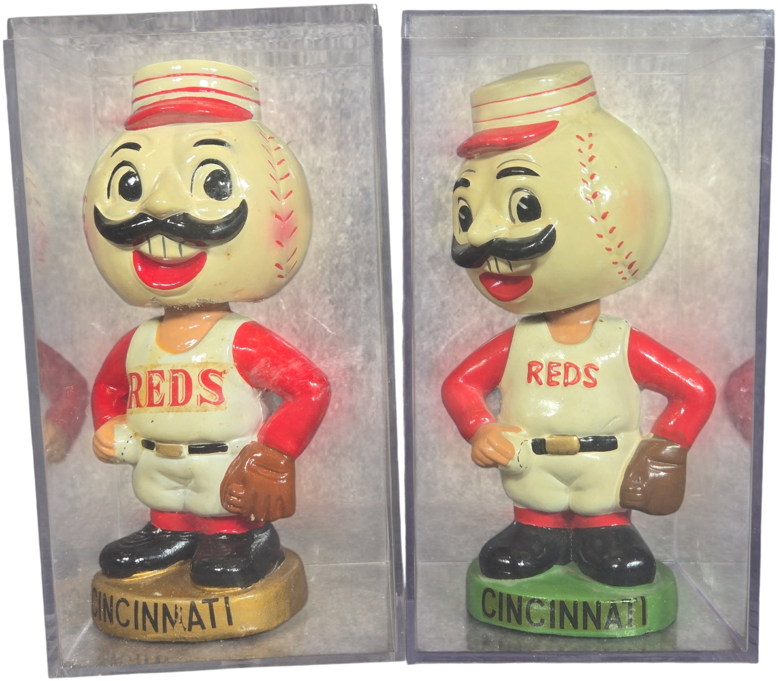 A Pair of Vintage Cincinnati Reds Mr. Red Bobbleheads by Sports Specialties Japan: This lot features a pair of vintage mascot bobbleheads, also known as nodders, representing Mr. Red of the Cincinnati Reds. These figures are constructed from a composition material, likely paper-mach