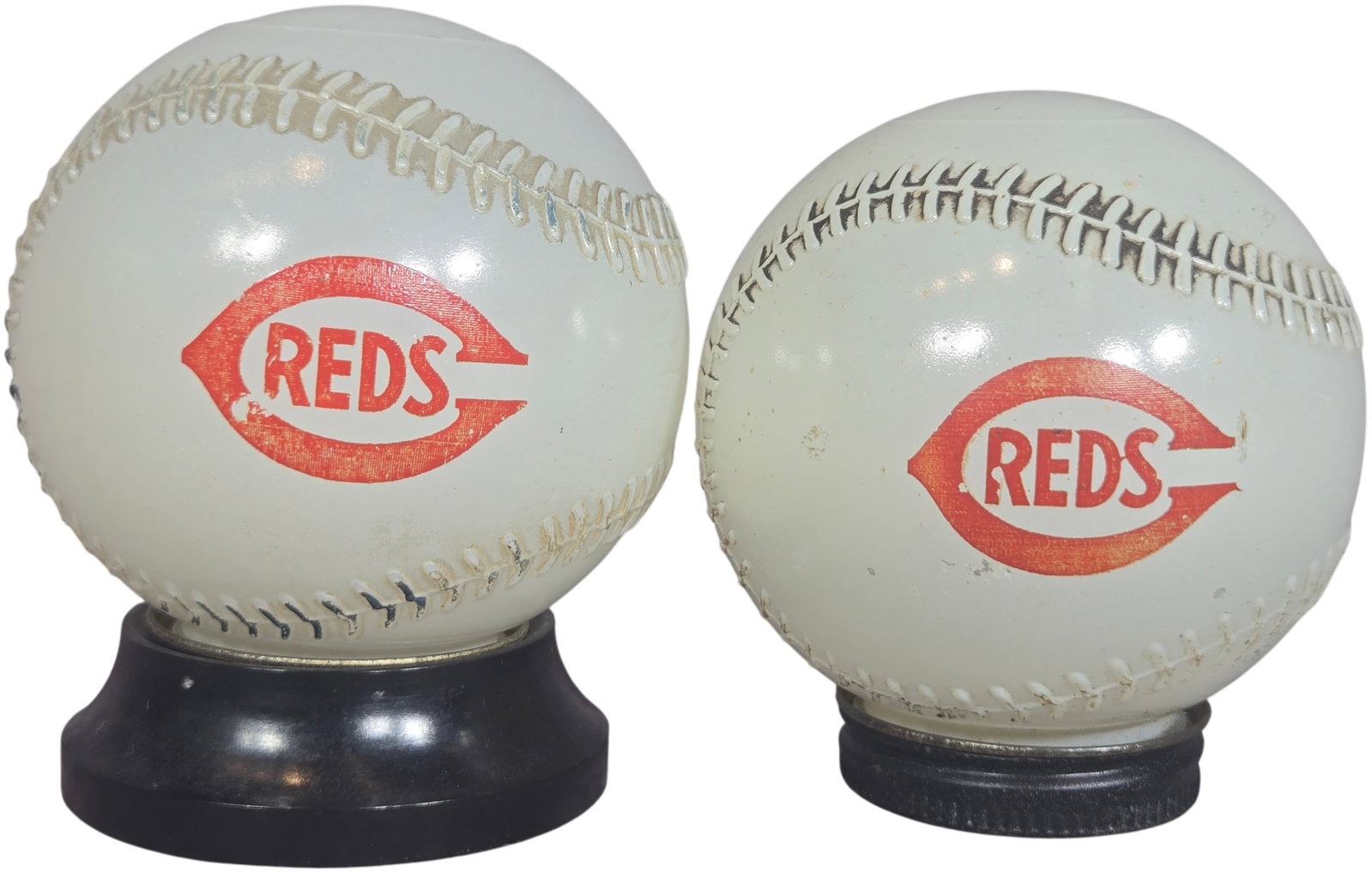 A Pair of Vintage Cincinnati Reds and Mobil Oil Pegasus Promotional Baseball Items: A pair of vintage promotional items designed as baseballs with molded recessed stitching. The pieces are constructed from a white, translucent material. A side of each item features a red Cincinnati R