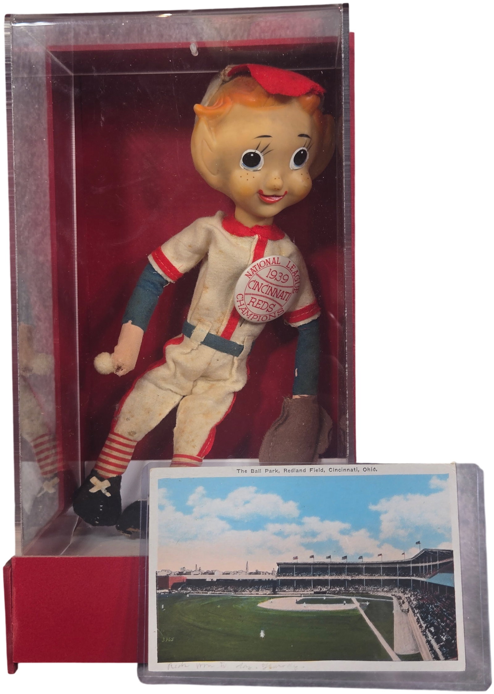 Cincinnati Reds Memorabilia Items Including 1939 Champions Mascot Doll and 1938 Redland Field: This lot features a vintage baseball mascot doll and a localized postcard associated with the Cincinnati Reds. The doll, attributed to mid-century Japanese manufacture, features a composition head wit