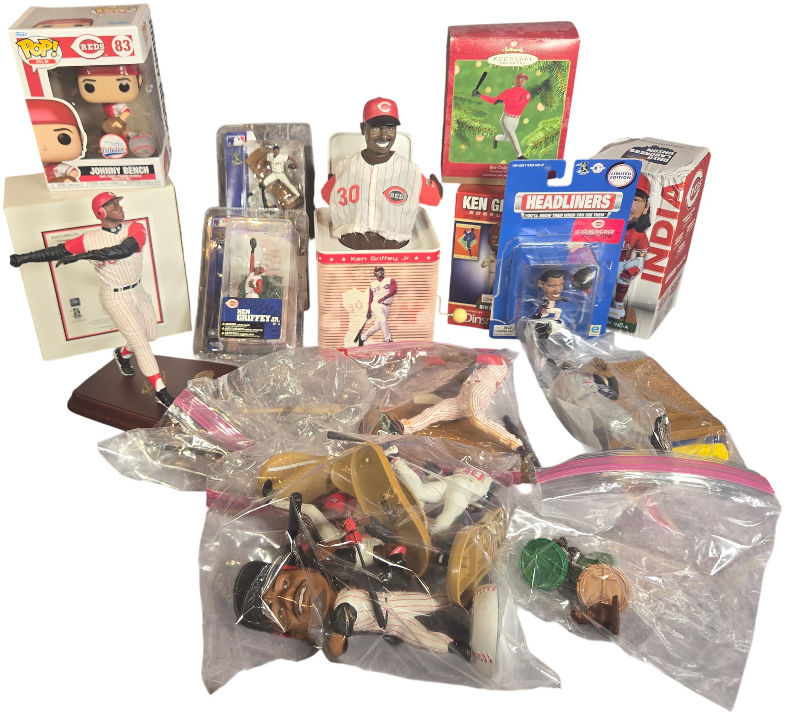 A Collection of Cincinnati Reds Baseball Memorabilia Featuring Ken Griffey Jr. and Others: This collection includes a diverse assortment of licensed Cincinnati Reds baseball collectibles, primarily highlighting Hall of Famer Ken Griffey Jr. The lot features several boxed and packaged items 