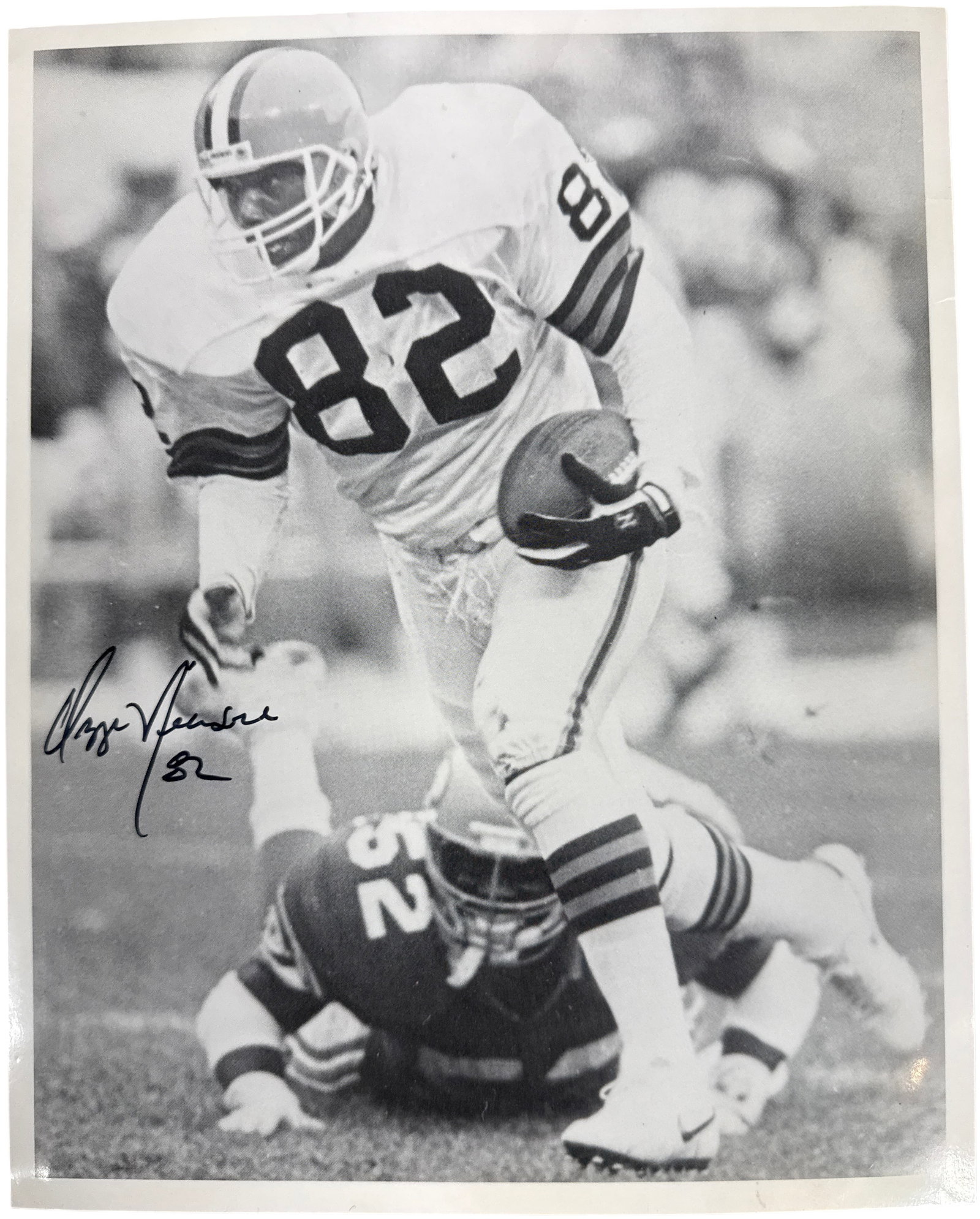 Autographed Ozzie Newsome Cleveland Browns Action Photograph: This is an autographed black and white photograph featuring Pro Football Hall of Fame tight end Ozzie Newsome of the Cleveland Browns. The action shot depicts Newsome carrying a football while being t