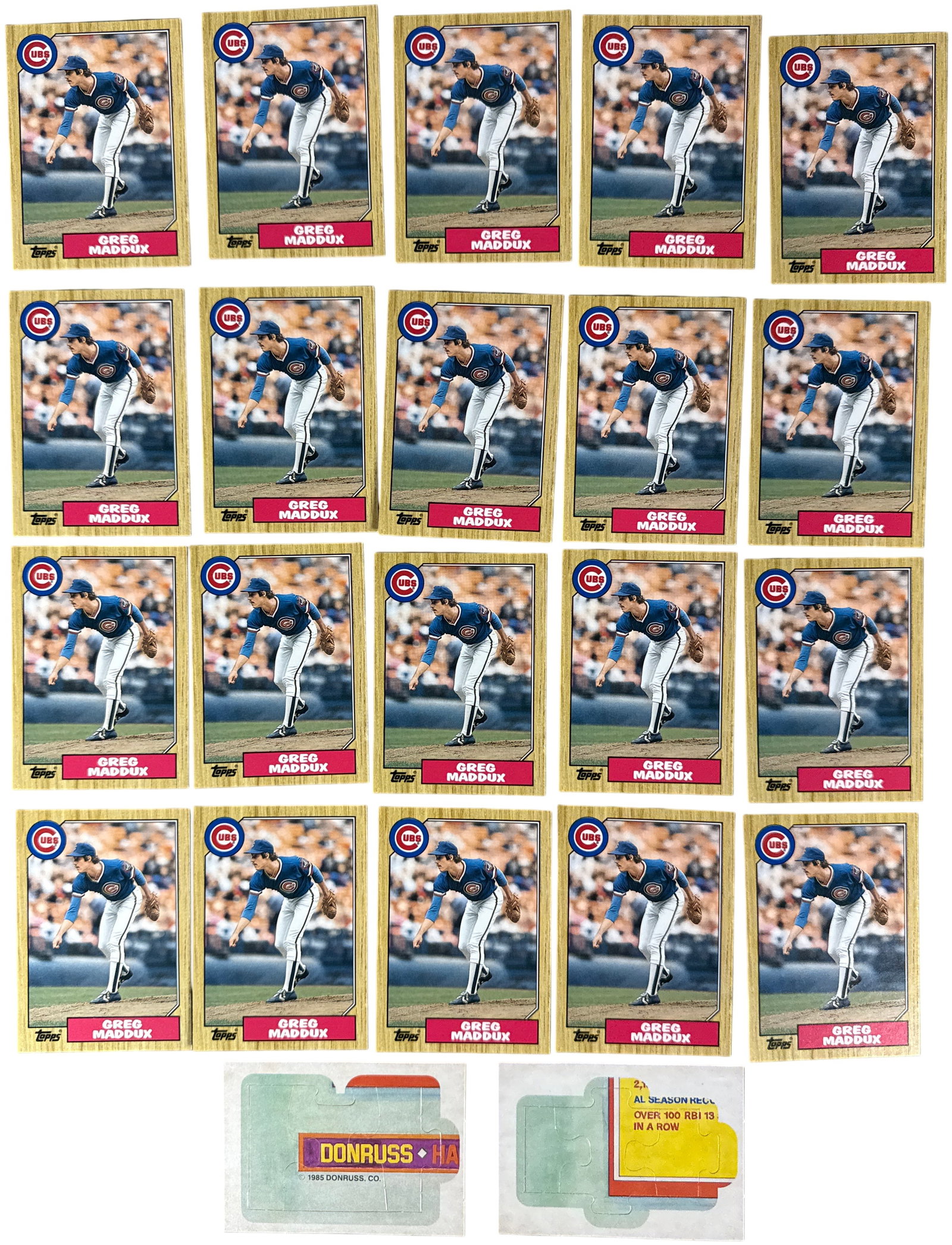 A Collection of 1987 Topps Greg Maddux Rookie Cards and Two 1985 Donruss Puzzle Pieces: This lot consists of examples of the 1987 Topps Greg Maddux rookie card, designated as card number 707. The cards feature the iconic 1987 wood-grain border design and depict Maddux in his Chicago Cubs