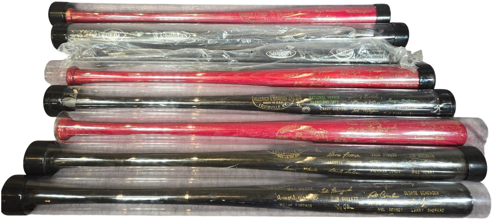 A Collection of Cincinnati Reds Commemorative and Souvenir Louisville Slugger Bats: This collection consists of commemorative and souvenir baseball bats produced by the Hillerich and Bradsby Company under the Louisville Slugger brand, primarily celebrating the Cincinnati Reds franchi