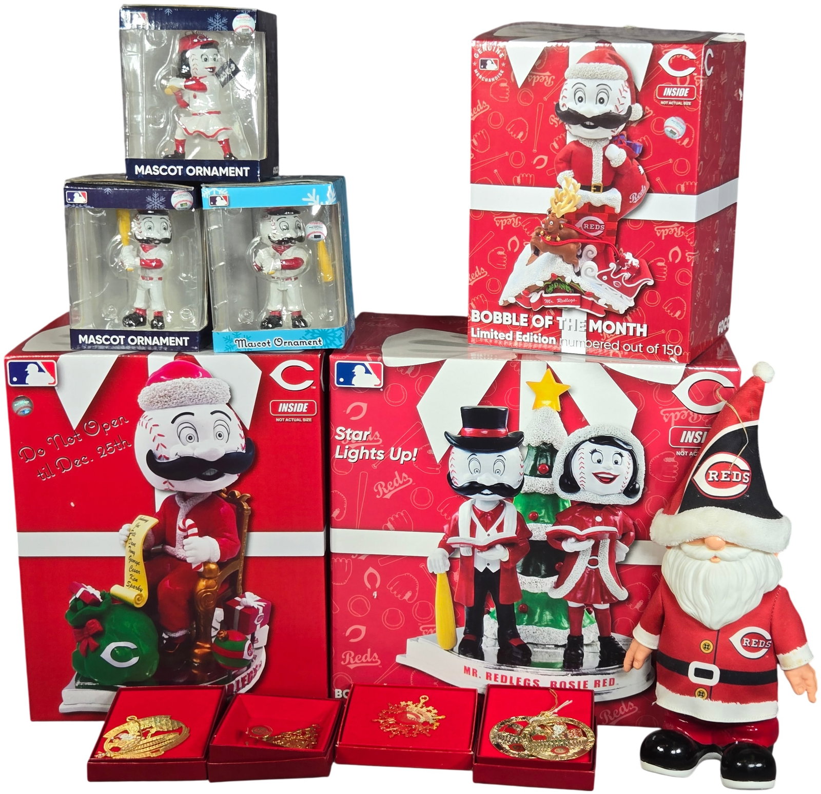 A Collection of Cincinnati Reds Holiday Themed Mascot Bobbleheads and Ornaments: This collection of Cincinnati Reds holiday-themed memorabilia features an assortment of limited edition bobbleheads, ornaments, and a plush figure. The grouping includes several Bobble of the Month ca